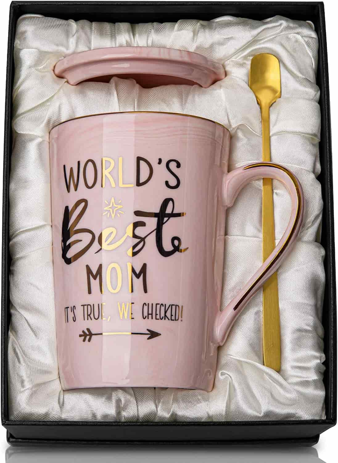 A pink ceramic mug with "World's Best Mom" text, matching lid, and a gold spoon, all presented in a gift box with a white satin lining.