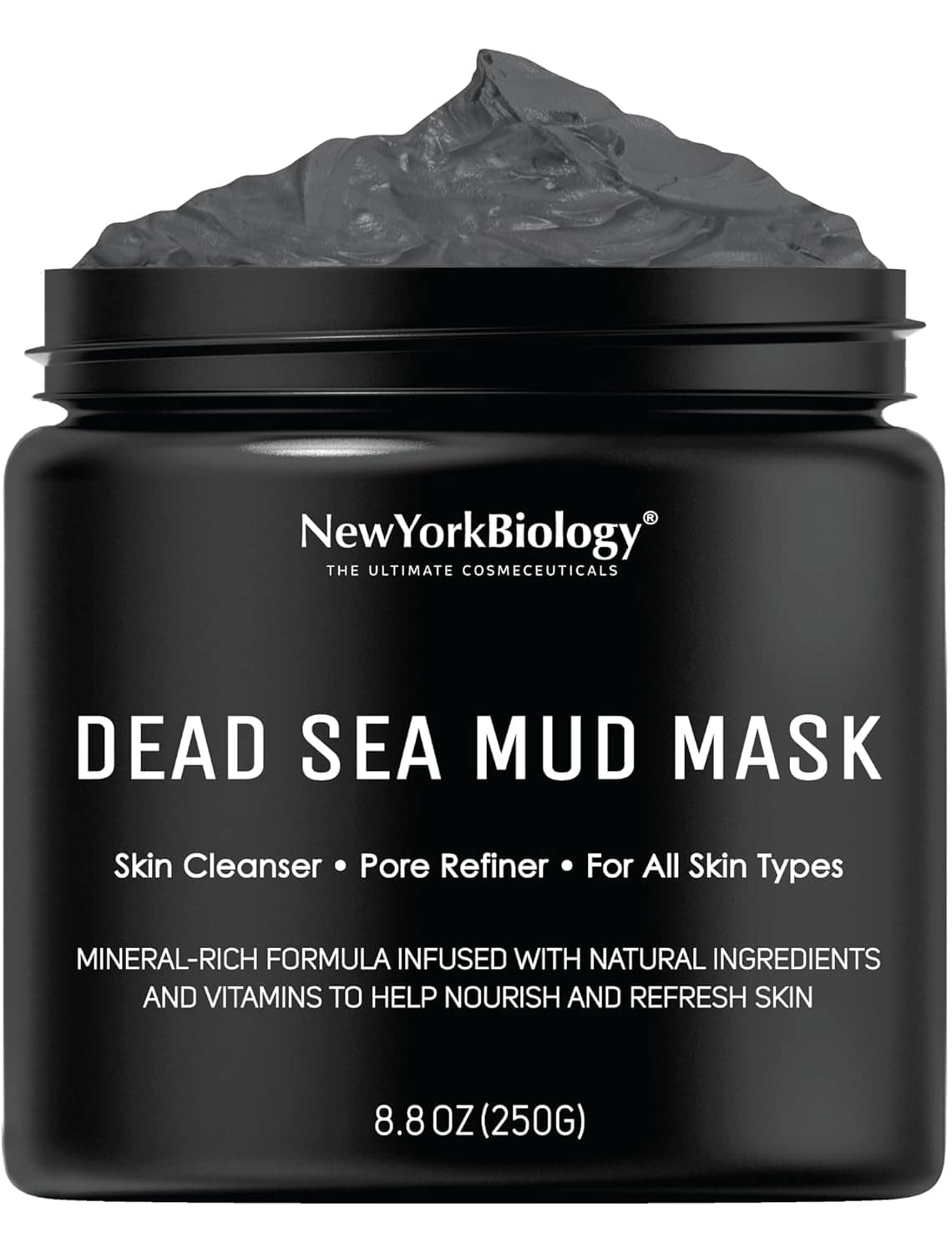 A black jar labeled "Dead Sea Mud Mask" from New York Biology, featuring product details and a visible mound of dark gray mud inside the open container.