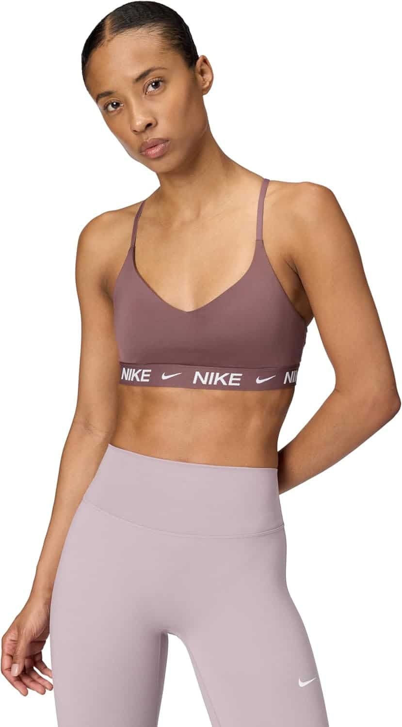 Woman wearing a mauve Nike sports bra and high-waisted lavender leggings, standing against a white background.