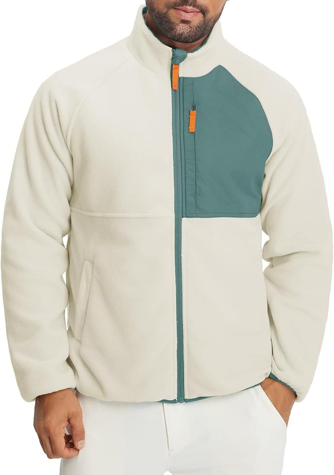 Man wearing a cream-colored fleece jacket with a teal chest pocket and zipper details, standing against a plain background.