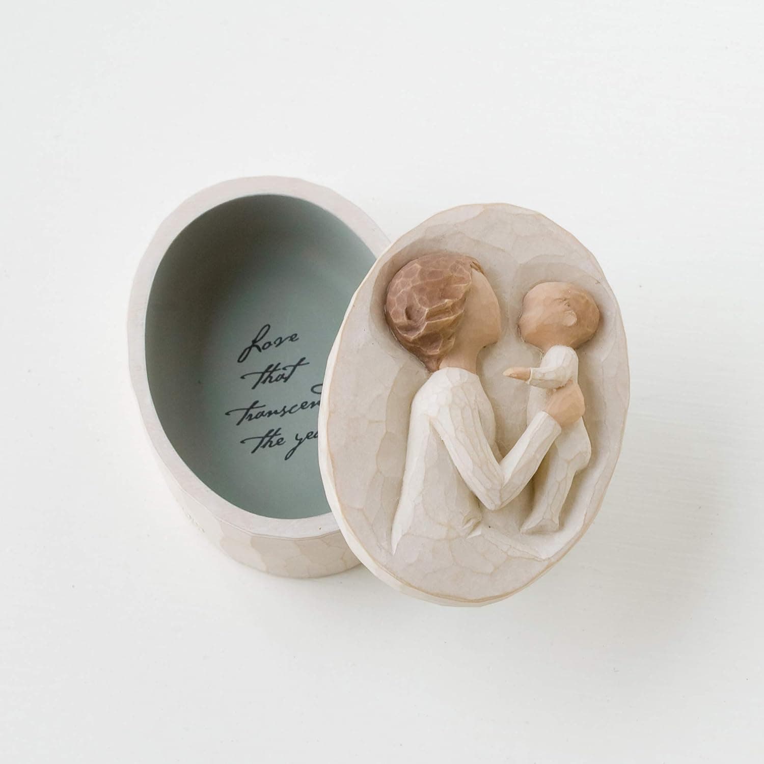 Oval trinket box with a carved image of a woman holding a baby on the lid; inside, cursive text reads, "Love that transcends the years.