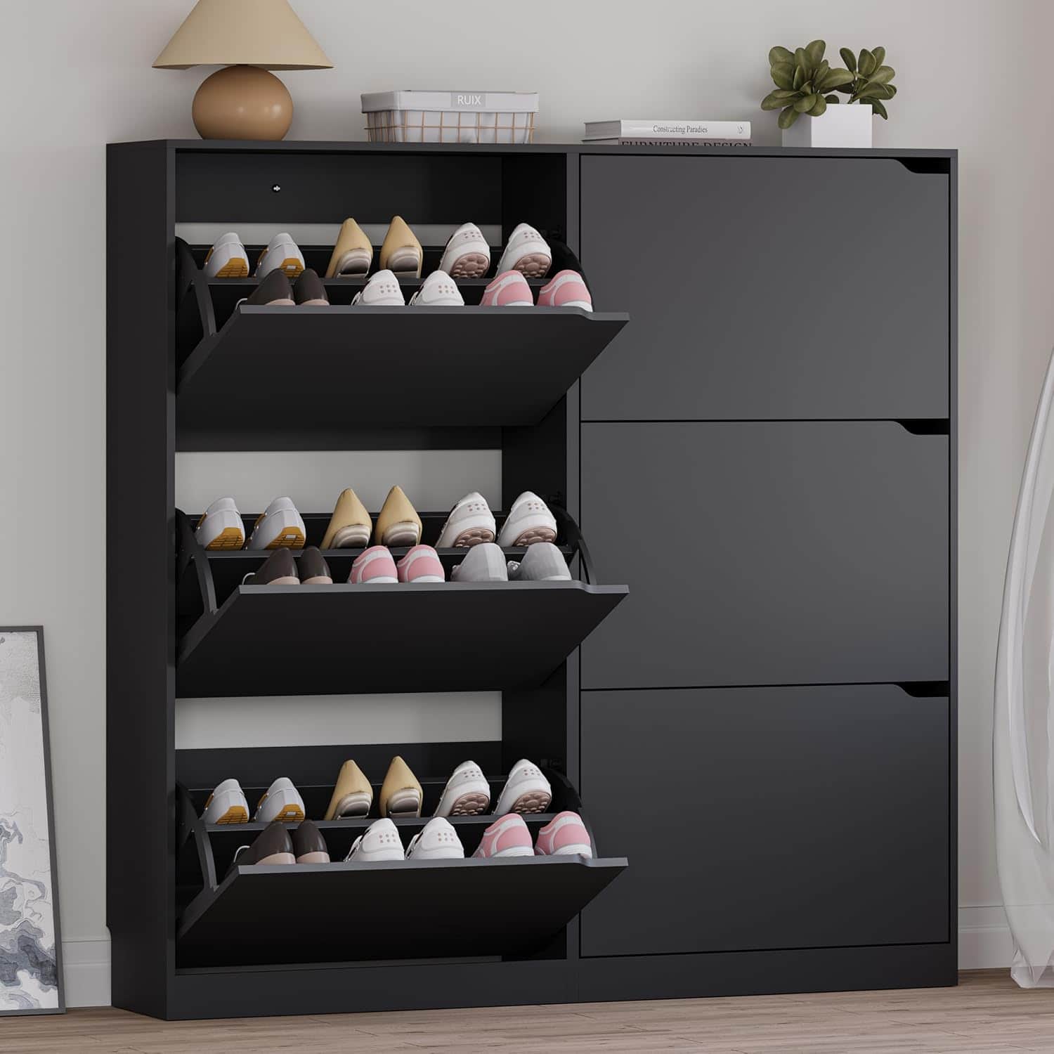 A black shoe cabinet with three pull-out drawers, each holding multiple pairs of shoes, stands against a wall with decor items on top.