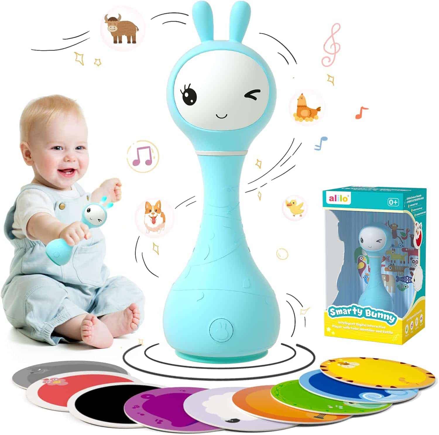 Baby playing with a blue bunny-shaped toy projector, surrounded by colorful discs and musical notes, with the toy's box and additional discs visible.