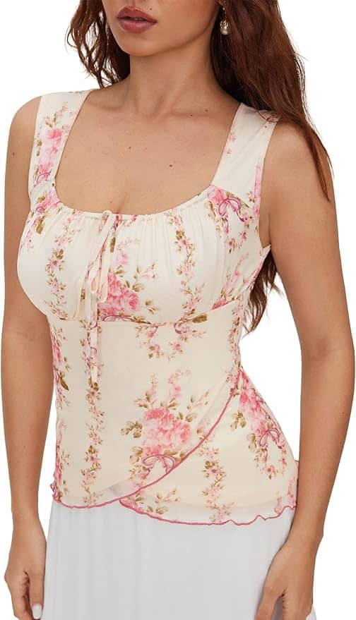 Woman wearing a sleeveless, scoop-neck floral blouse with pink and beige tones, featuring a decorative tie at the neckline and a fitted waist.