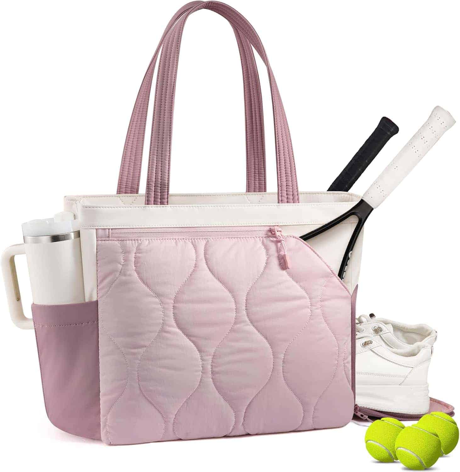 A pink and white tote bag holds two tennis rackets and a water bottle. White sneakers and two tennis balls are placed next to the bag.