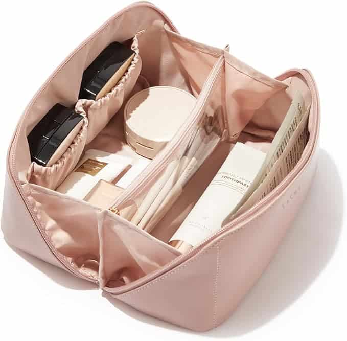 Open pink cosmetic bag neatly organized with makeup products, brushes, and skincare items inside multiple compartments.