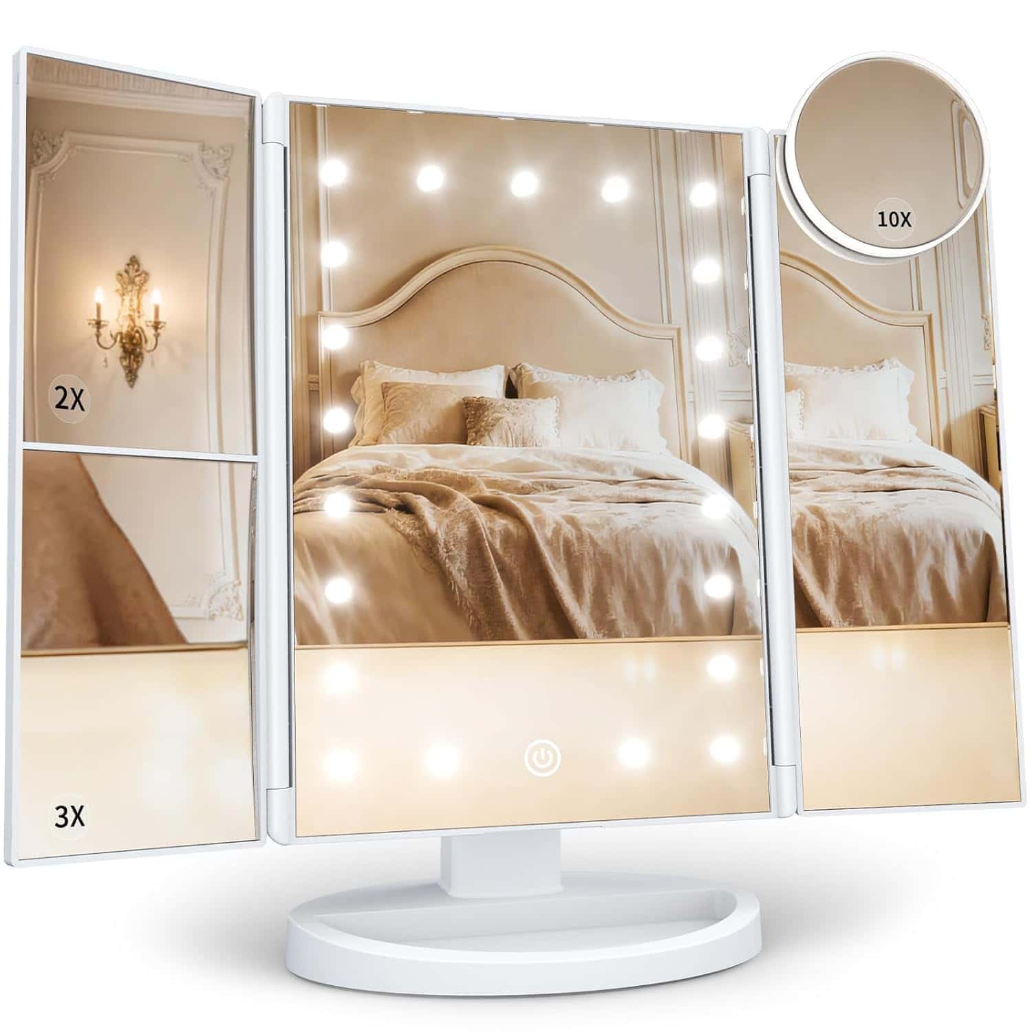 Tri-fold vanity mirror with LED lights, magnification panels labeled 2X, 3X, and 10X, reflecting a bedroom with a bed, pillows, and a wall sconce.