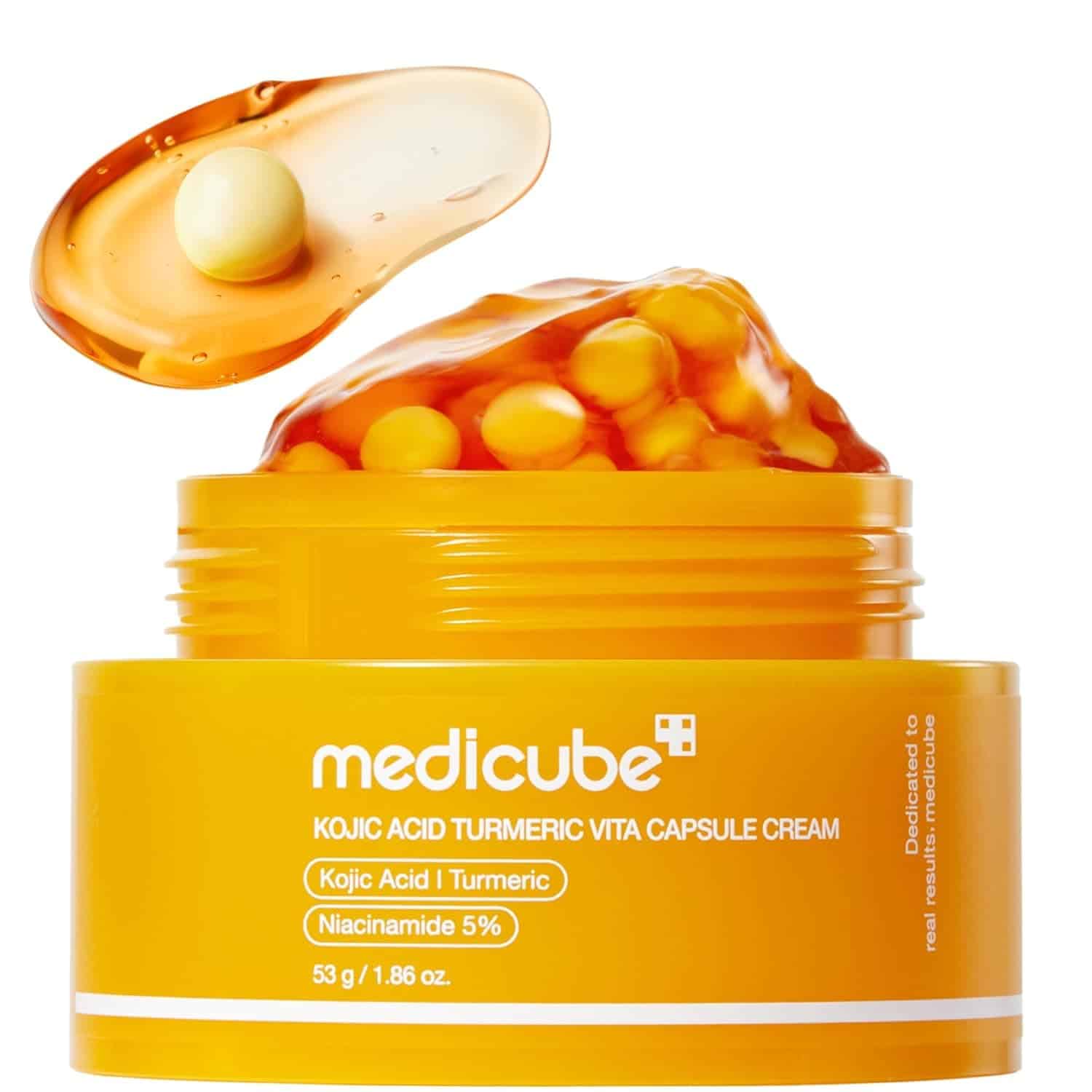 An open jar of Medicube Kojic Acid Turmeric Vita Capsule Cream with yellow capsules and a product sample on a spatula, against a white background.