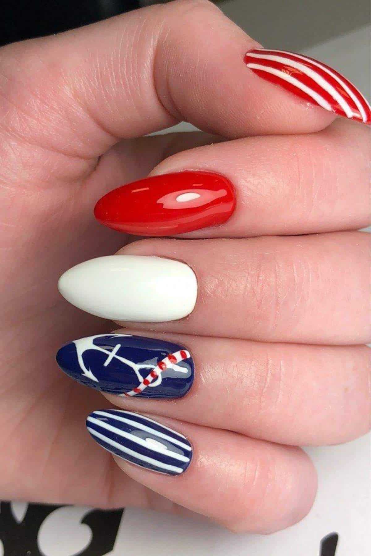 A hand with manicured nails painted in red, white, and blue with striped and baseball-themed designs on each nail.