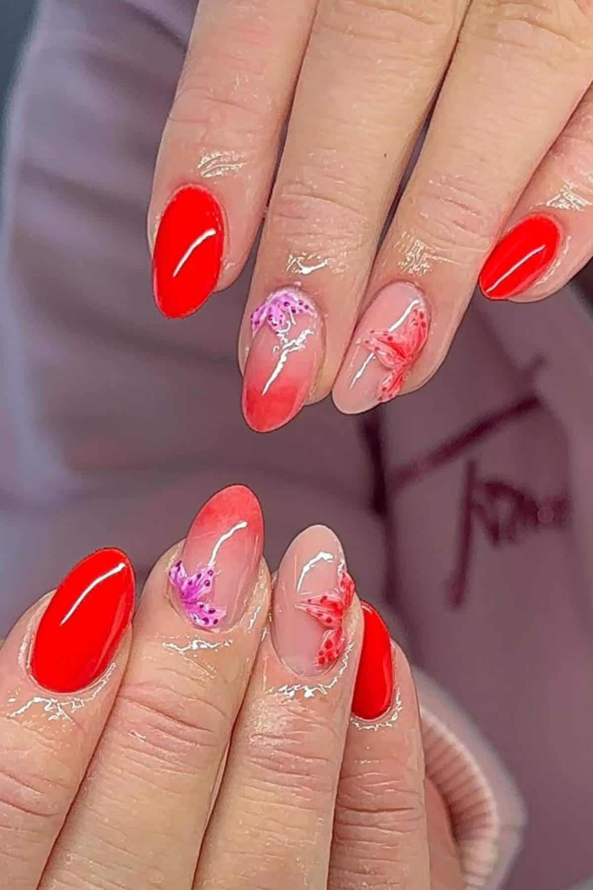 Hands with manicured nails featuring a mix of glossy red polish and nude base with pink and red floral designs.