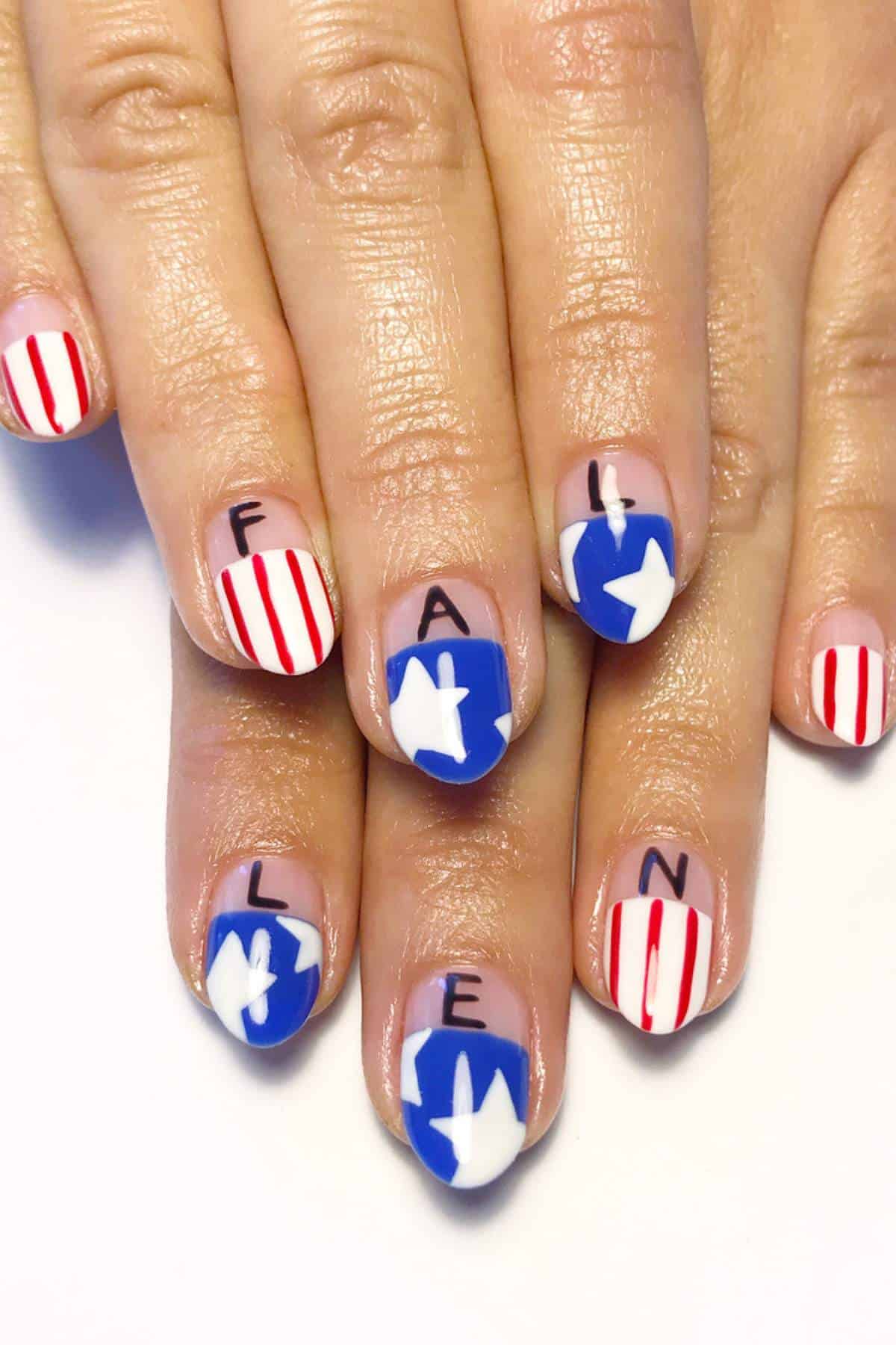 Fingernails with patriotic nail art: red and white stripes, blue with white stars, and letters spelling "FALLEN" across the nails.