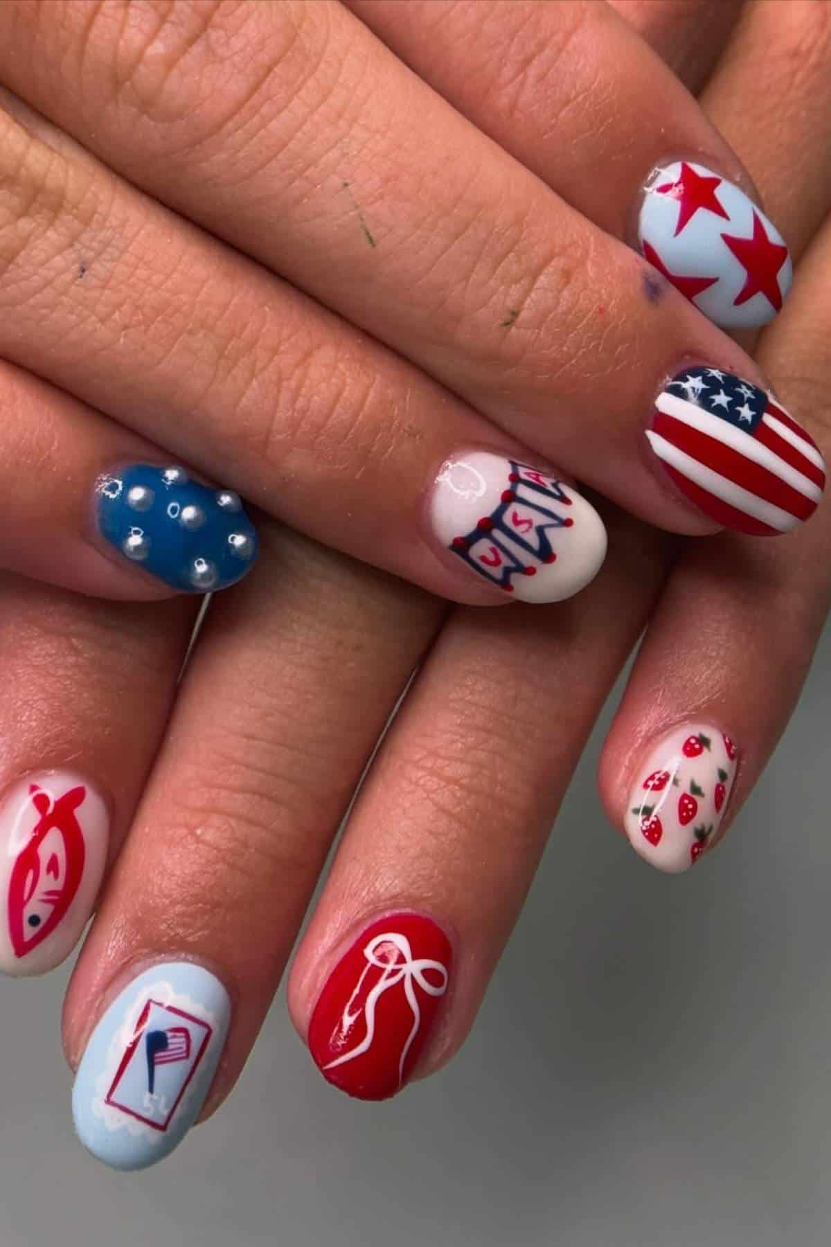 Close-up of hands with manicured nails featuring various patriotic and festive designs, including stars, stripes, polka dots, strawberries, bows, and red fish.