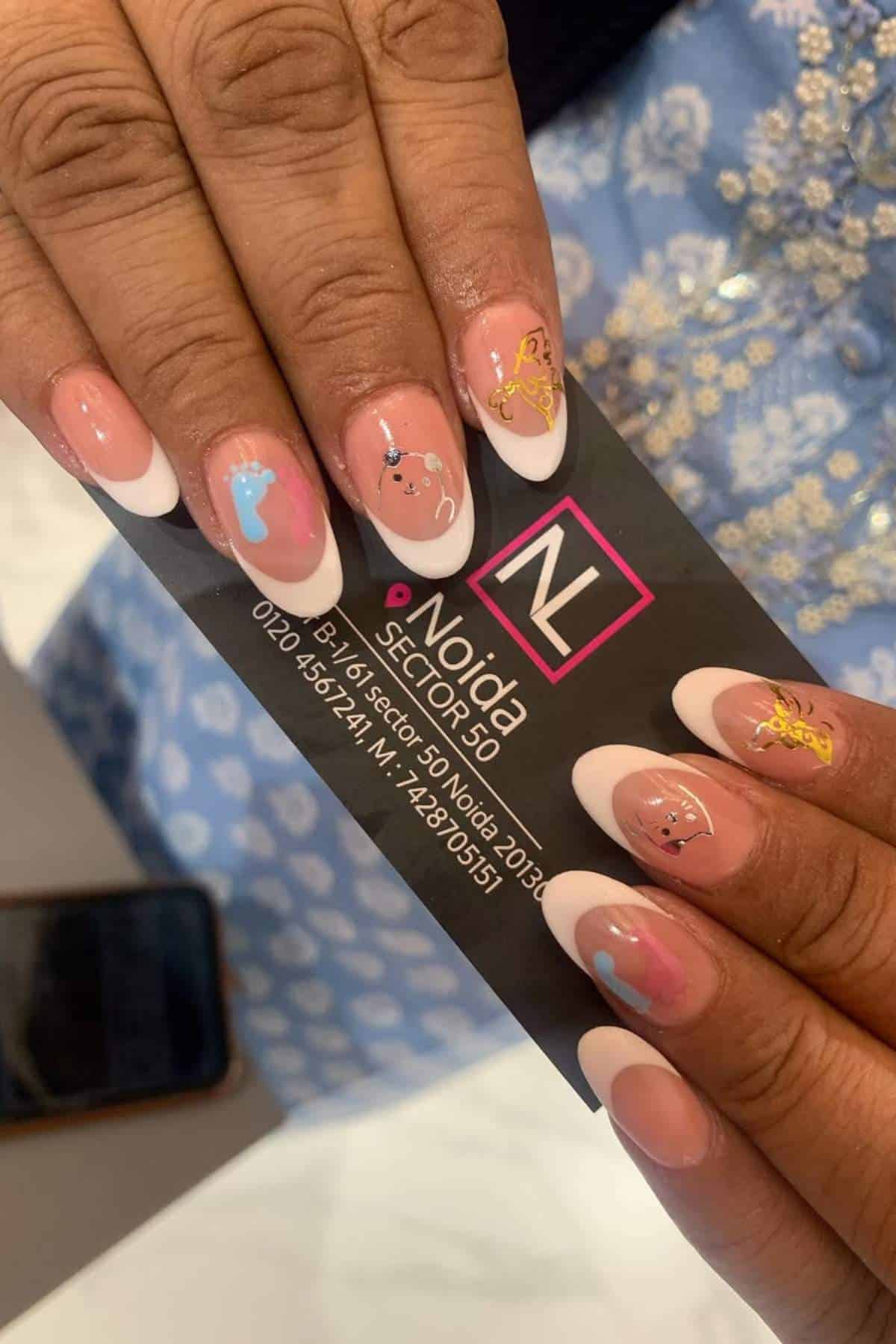Hands with almond-shaped French manicure and small nail art designs hold a black business card for "Noida Sector 51" nail salon.