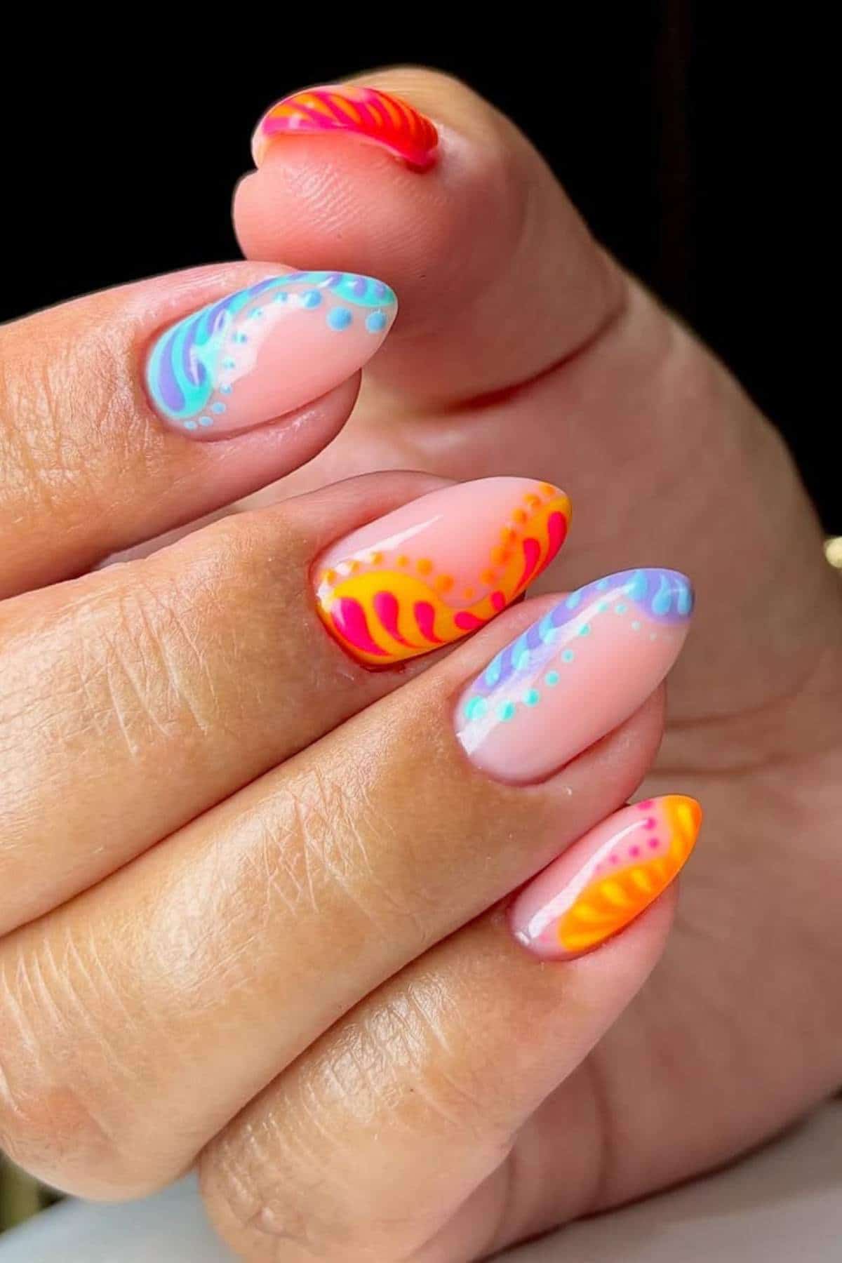 A hand with almond-shaped nails featuring colorful, abstract designs in orange, yellow, red, and blue on a nude base.