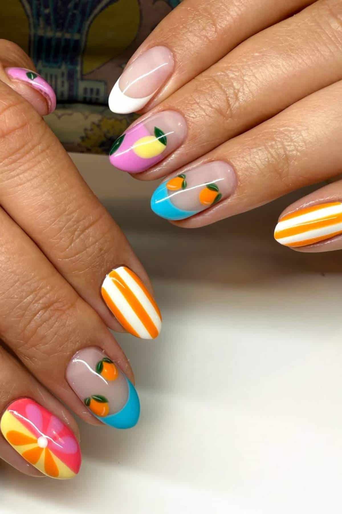 Hands with almond-shaped nails featuring colorful summer-themed nail art, including stripes, fruit designs, French tips, and vibrant abstract patterns.