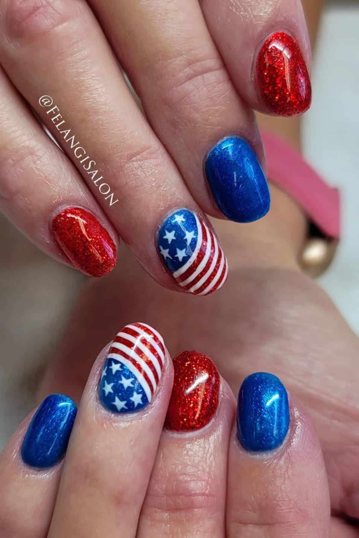 Hands with manicured nails painted in red glitter, blue, and American flag designs with white stars and stripes.