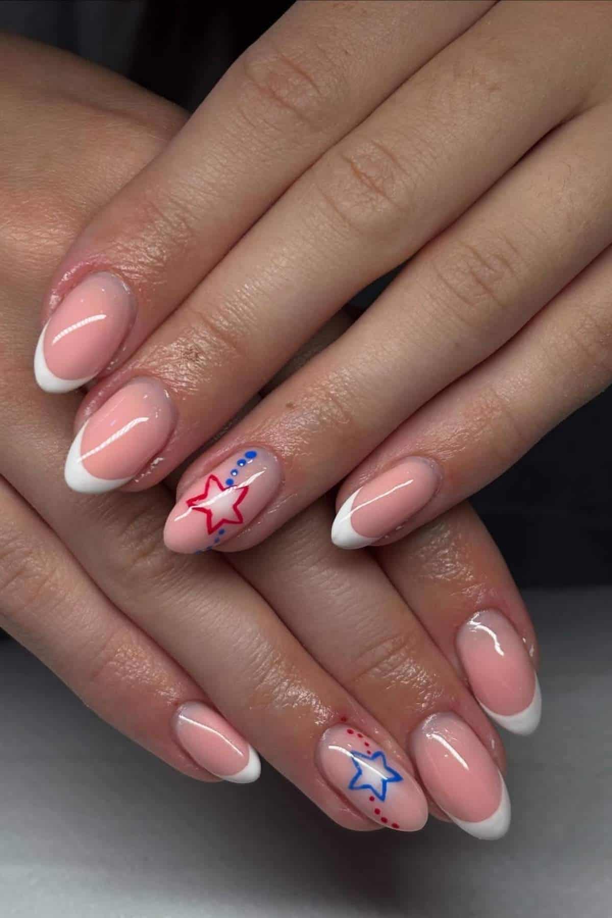 Hands with a French manicure, featuring red and blue star designs and dots on the ring and pinky fingernails.