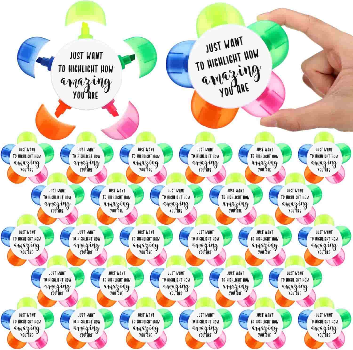Multiple colorful flower-shaped highlighters, each with a central label that reads “Just want to highlight how amazing you are.” A hand holds one highlighter at the top right.
