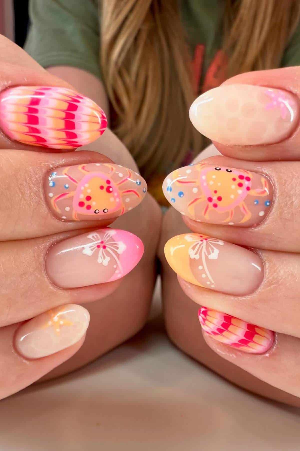 Close-up of hands with colorful, detailed nail art featuring crabs, seashells, butterflies, dots, and pastel gradients in pink, orange, yellow, and blue tones.