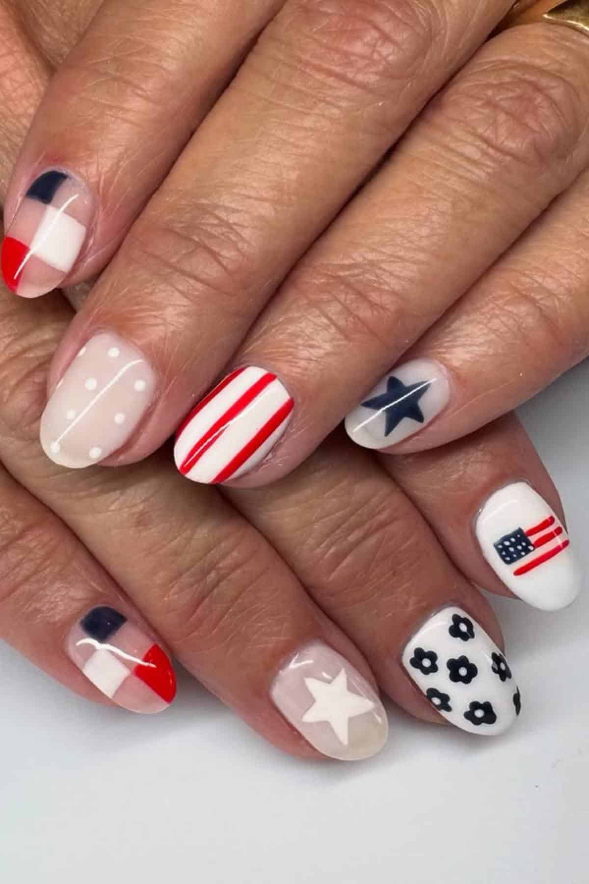 Close-up of hands with manicure featuring American flag-inspired designs, including stars, stripes, dots, and floral patterns in red, white, and blue.