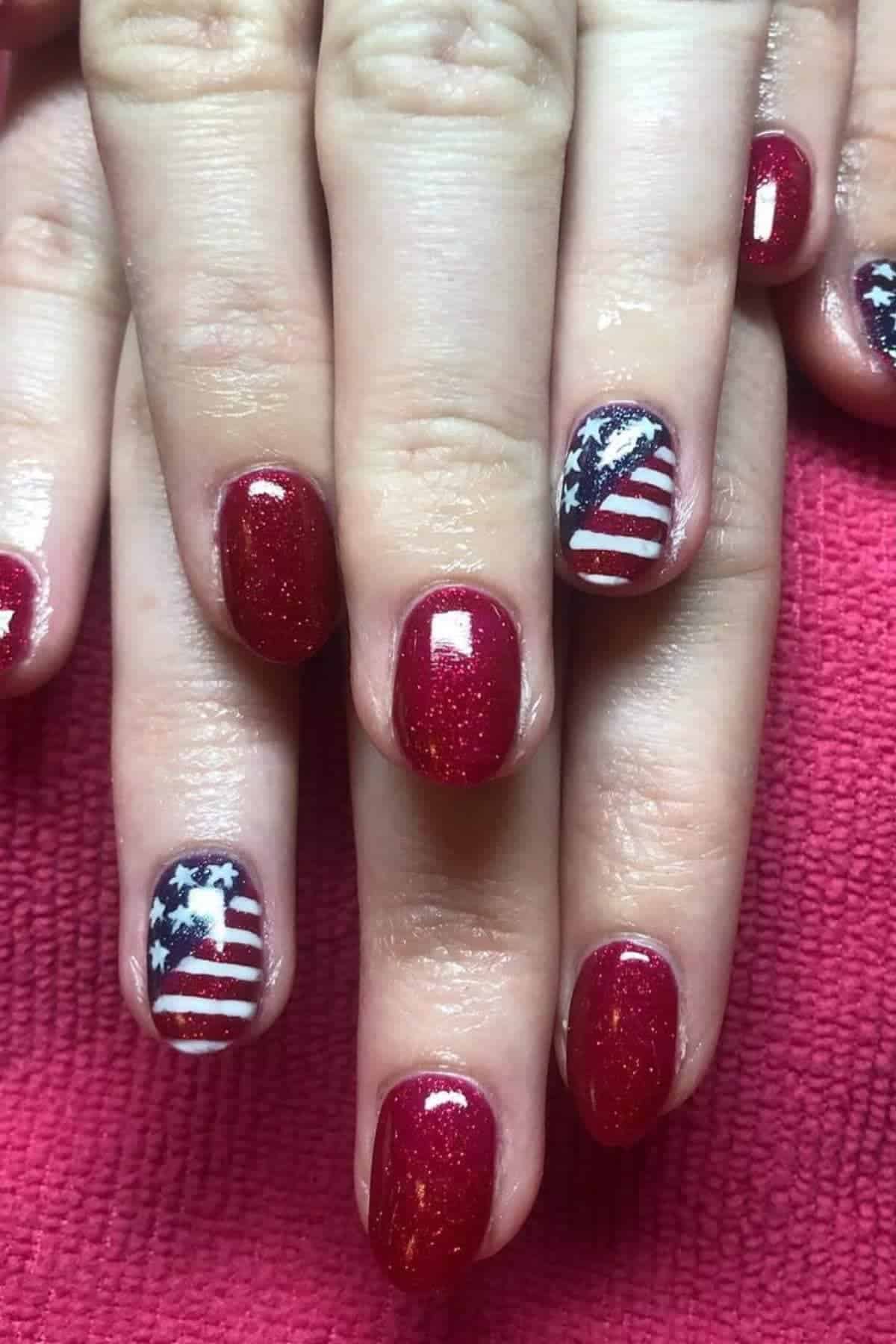Close-up of hands with red glittery nail polish; ring fingers feature an American flag design with stars and stripes.