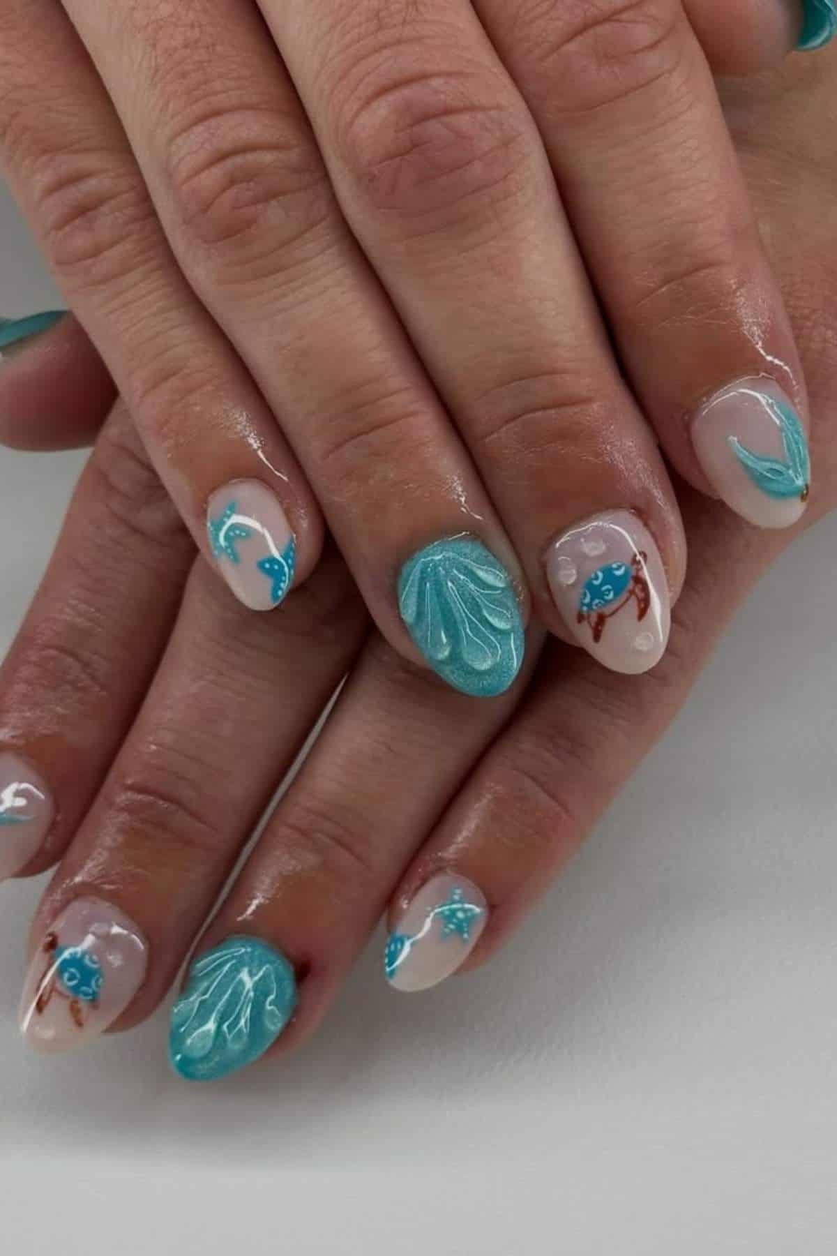 Hands with manicured nails featuring blue ocean-themed designs, including seashells, crabs, starfish, and waves on a nude and turquoise base.