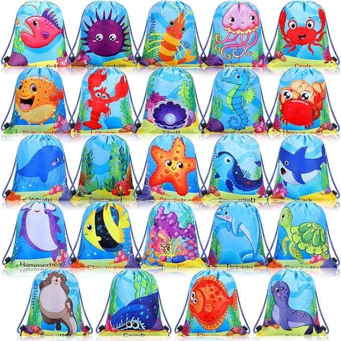 Twenty brightly colored drawstring bags are arranged in a grid, each featuring a different cartoon sea creature on a blue ocean-themed background.