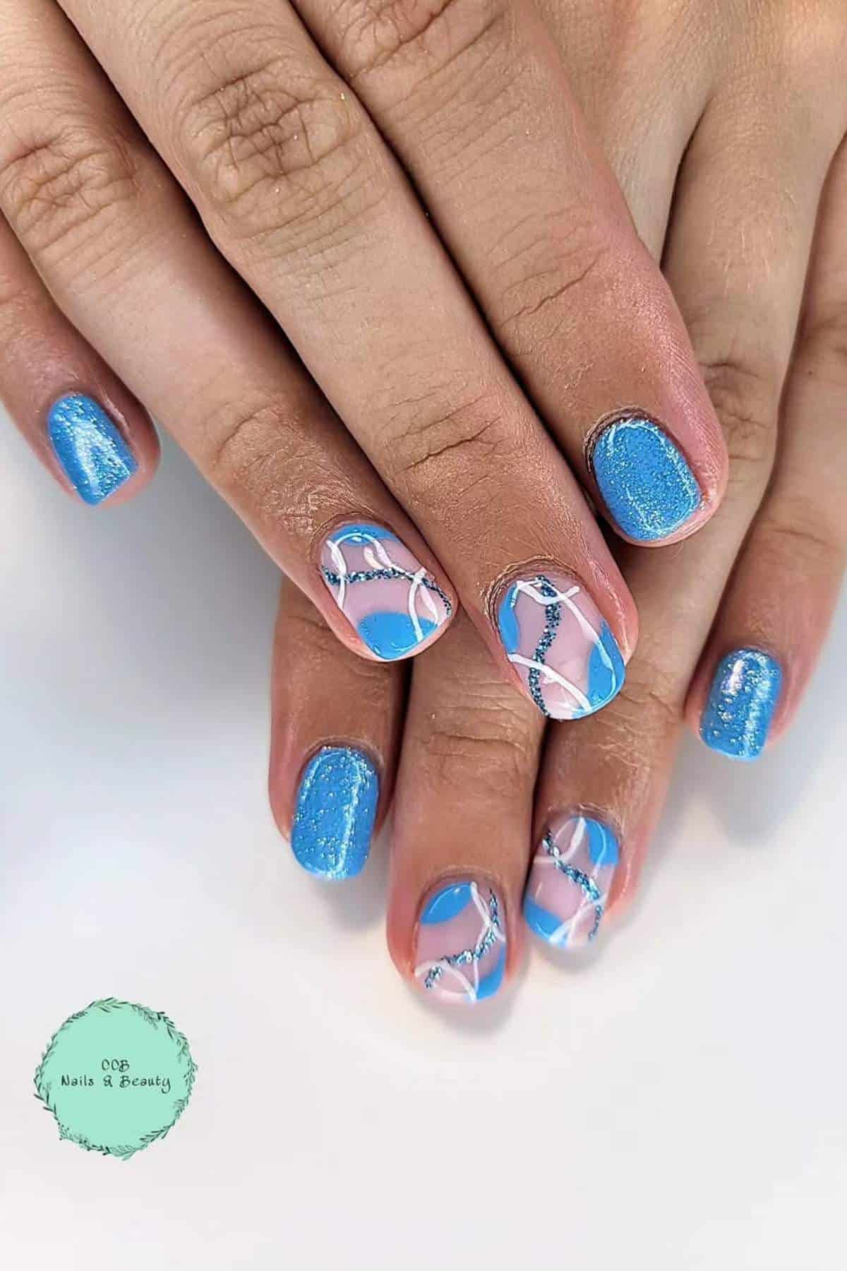 Hands with short nails painted blue, two accent nails on each hand featuring abstract pink, white, and silver line designs.