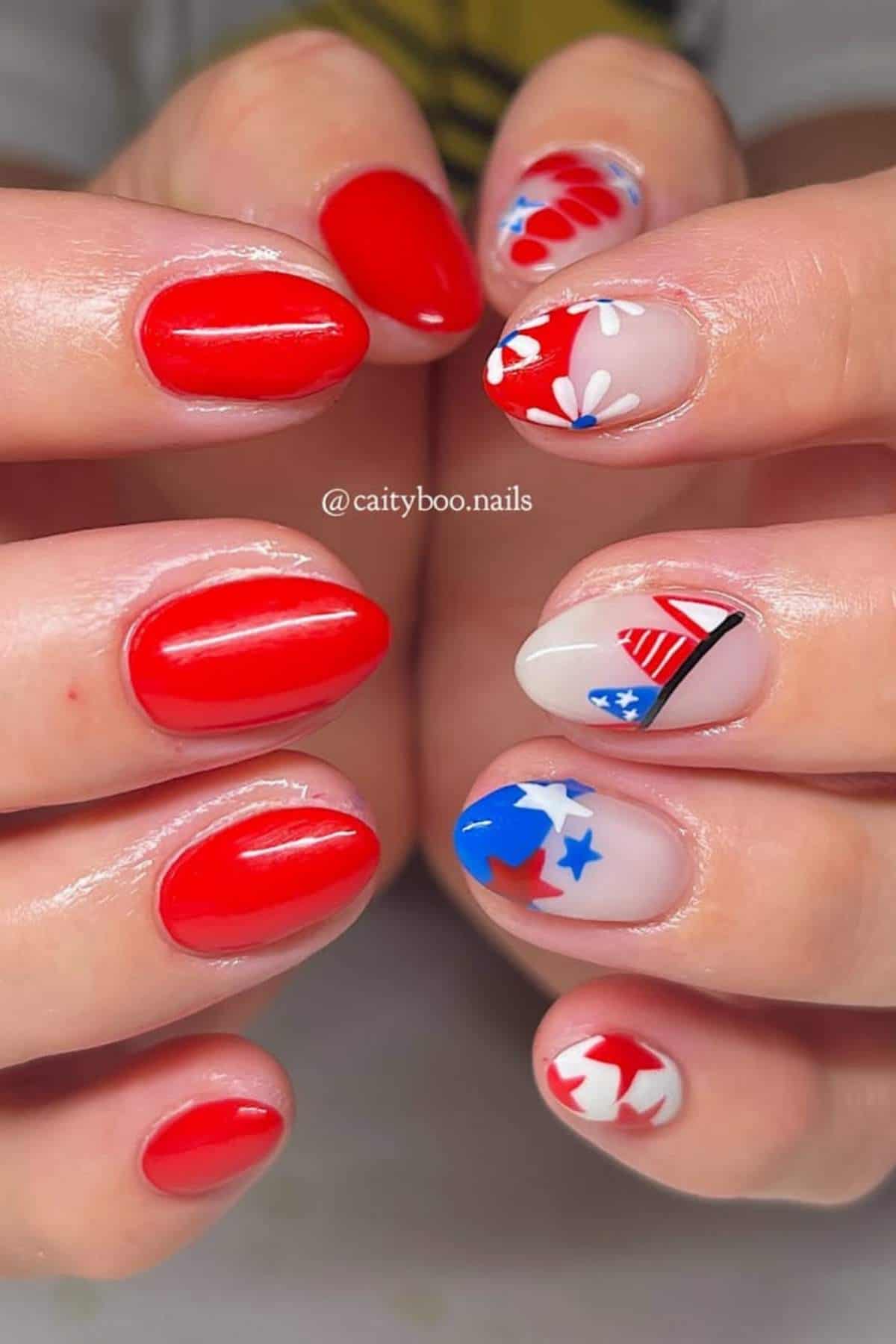 Hands with red, white, and blue nail art featuring stars, stripes, flowers, and abstract patterns on almond-shaped nails.