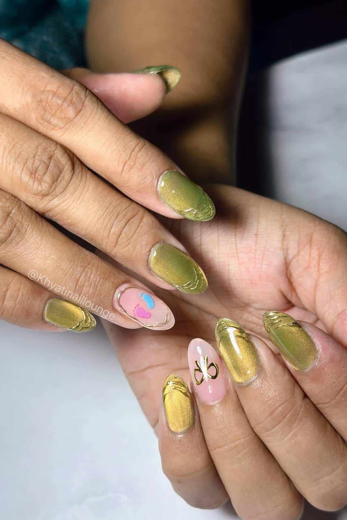 Hands with gold chrome nails, one accent nail on each hand featuring minimal designs: a heart with a dot on one and a butterfly shape on the other.