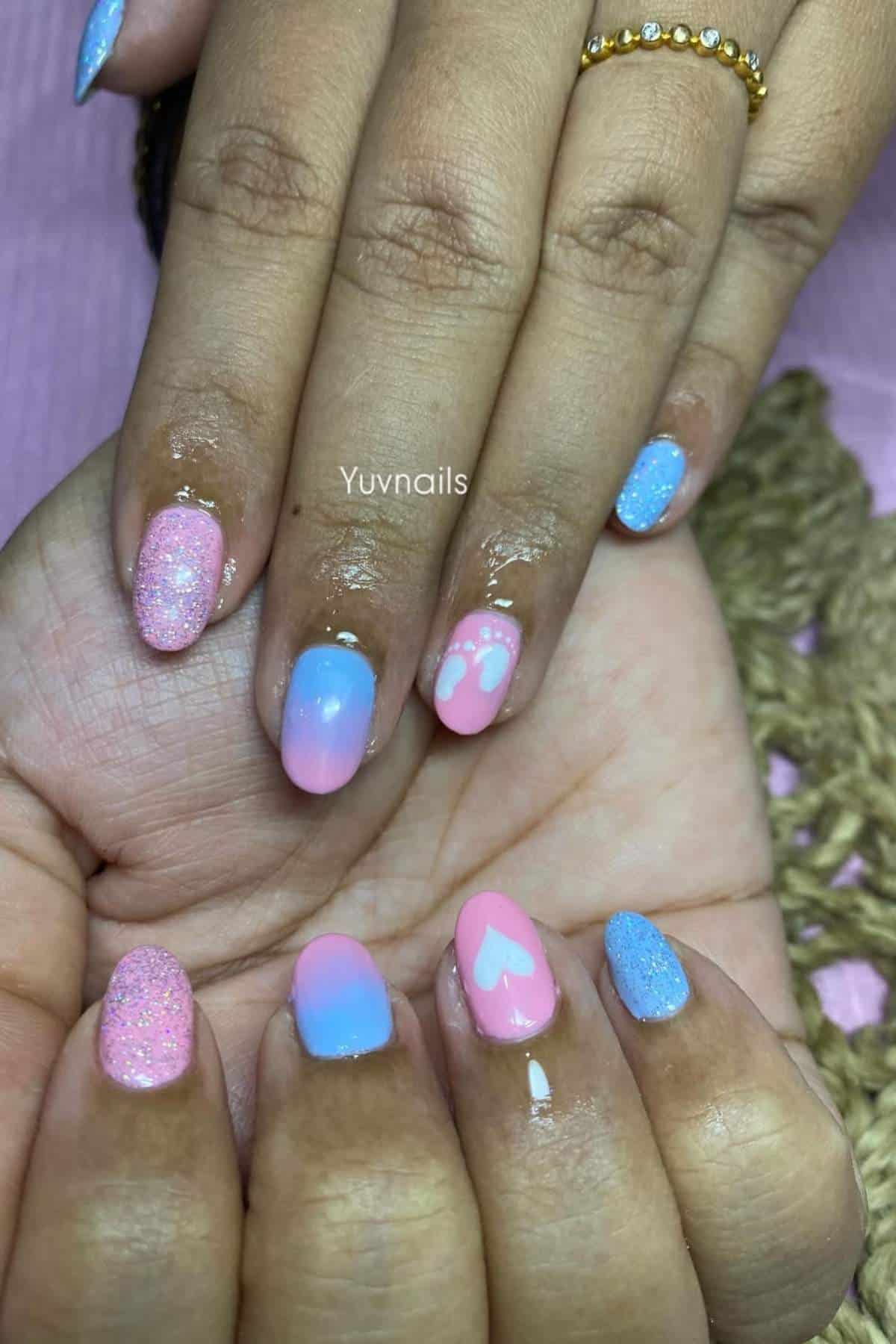 Hands with manicured nails featuring pink, blue, and purple ombre designs, glitter accents, and white heart shapes.