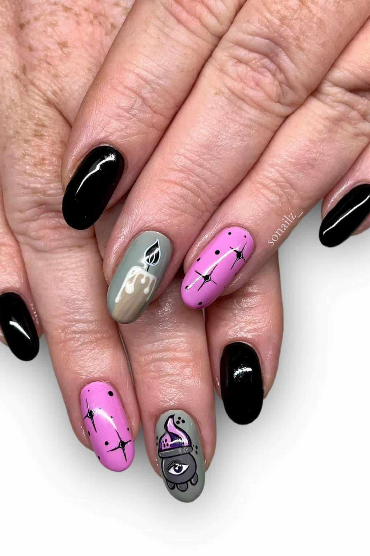 Hands with manicured nails; some nails are painted black, while others feature abstract pink and gray designs, including an eye, drips, and dotted lines.