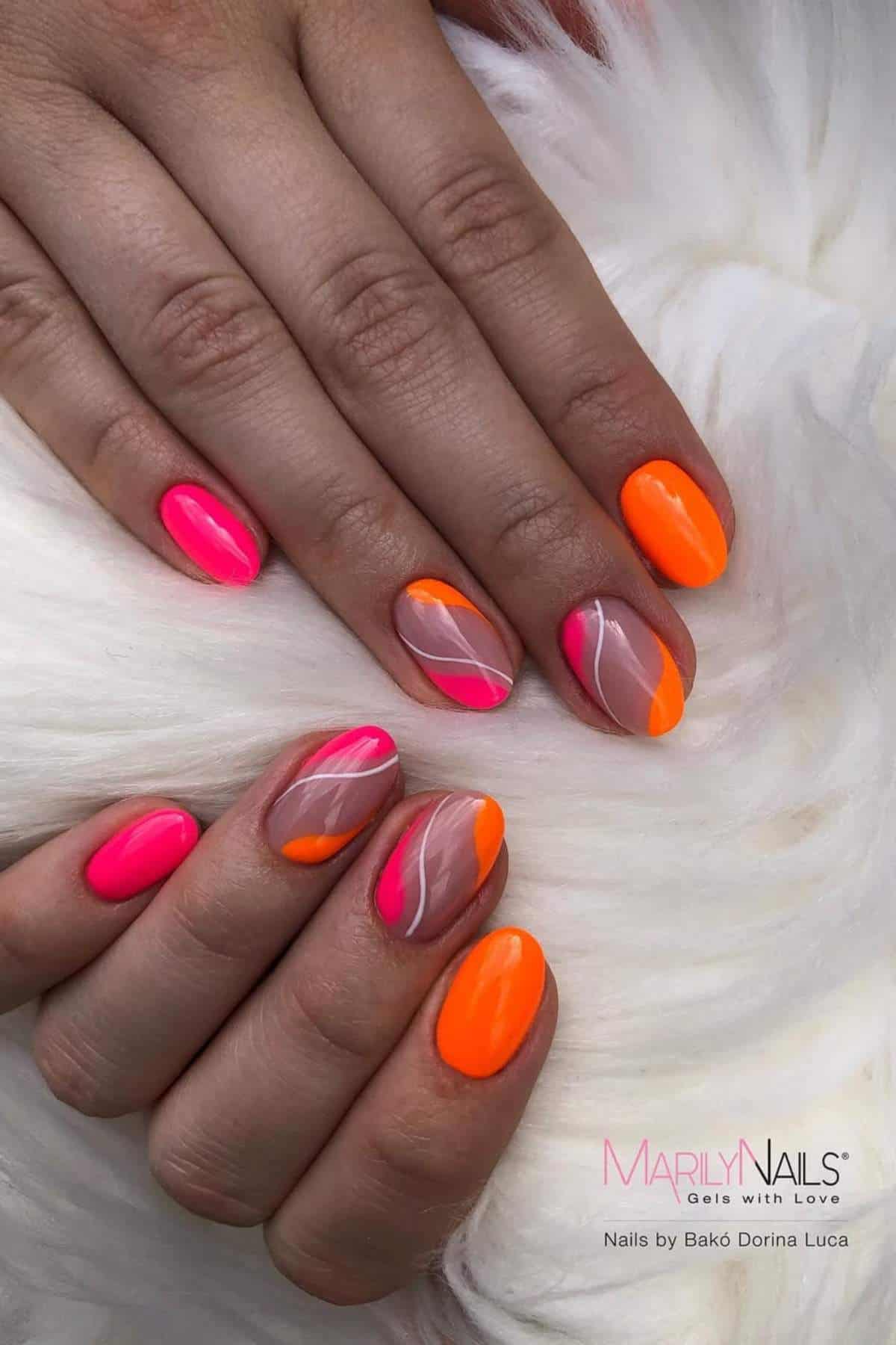 Hands with short oval nails featuring neon pink and orange polish, some with abstract designs and nude base, displayed on a white faux fur surface.