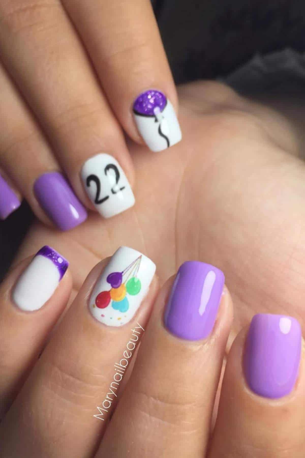 Close-up of hands with purple and white nail art, featuring balloons, the number "22," and a purple balloon design on accent nails.