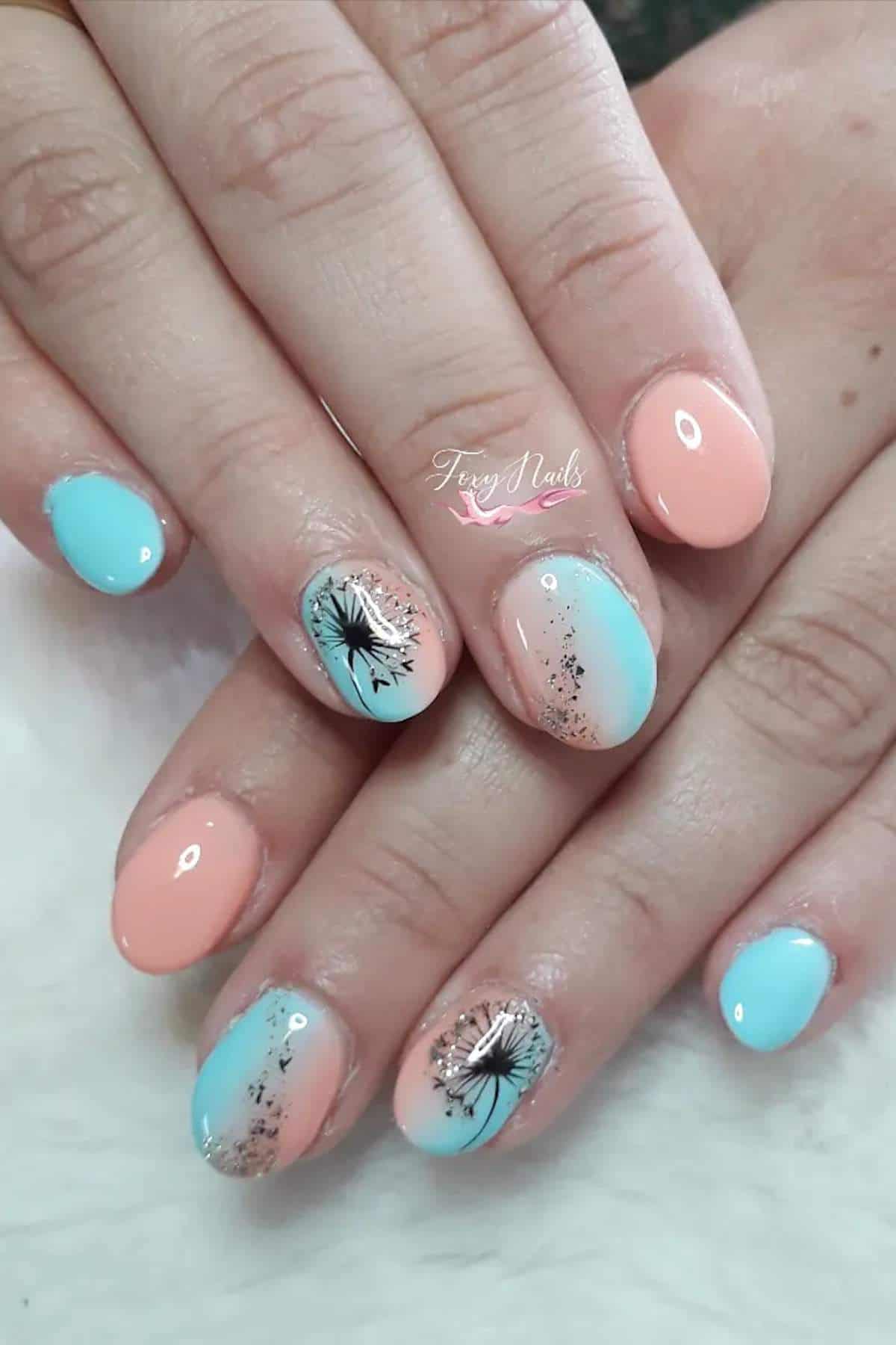 Hands with short nails painted in pastel blue and peach colors; some nails feature dandelion and glitter accent designs.