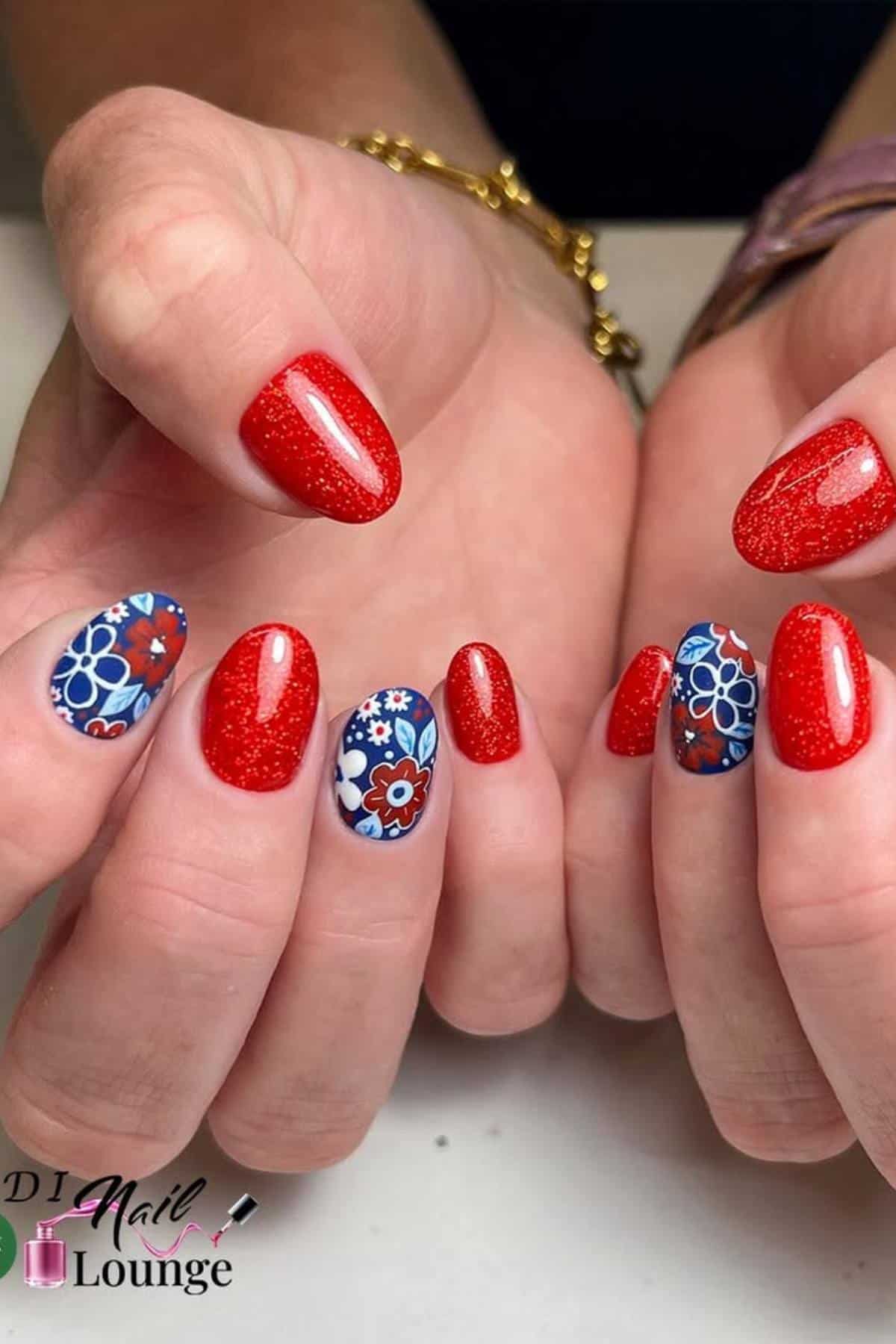 Hands with red glittery nail polish; accent nails feature blue and white floral designs. A gold bracelet and watch are visible on the wrists.