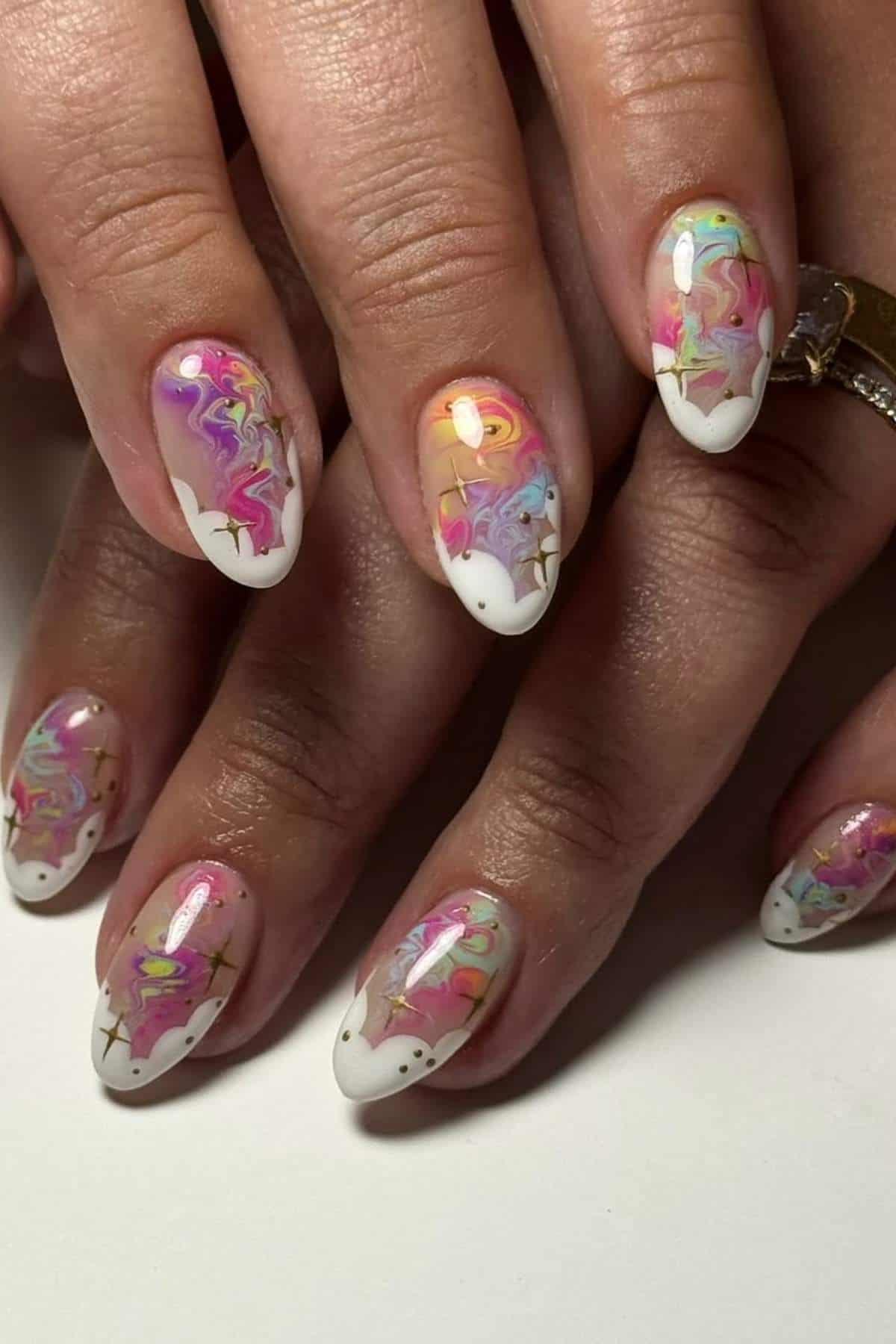 Hands with almond-shaped nails featuring colorful marble nail art, white tips, gold accents, and small dot designs.