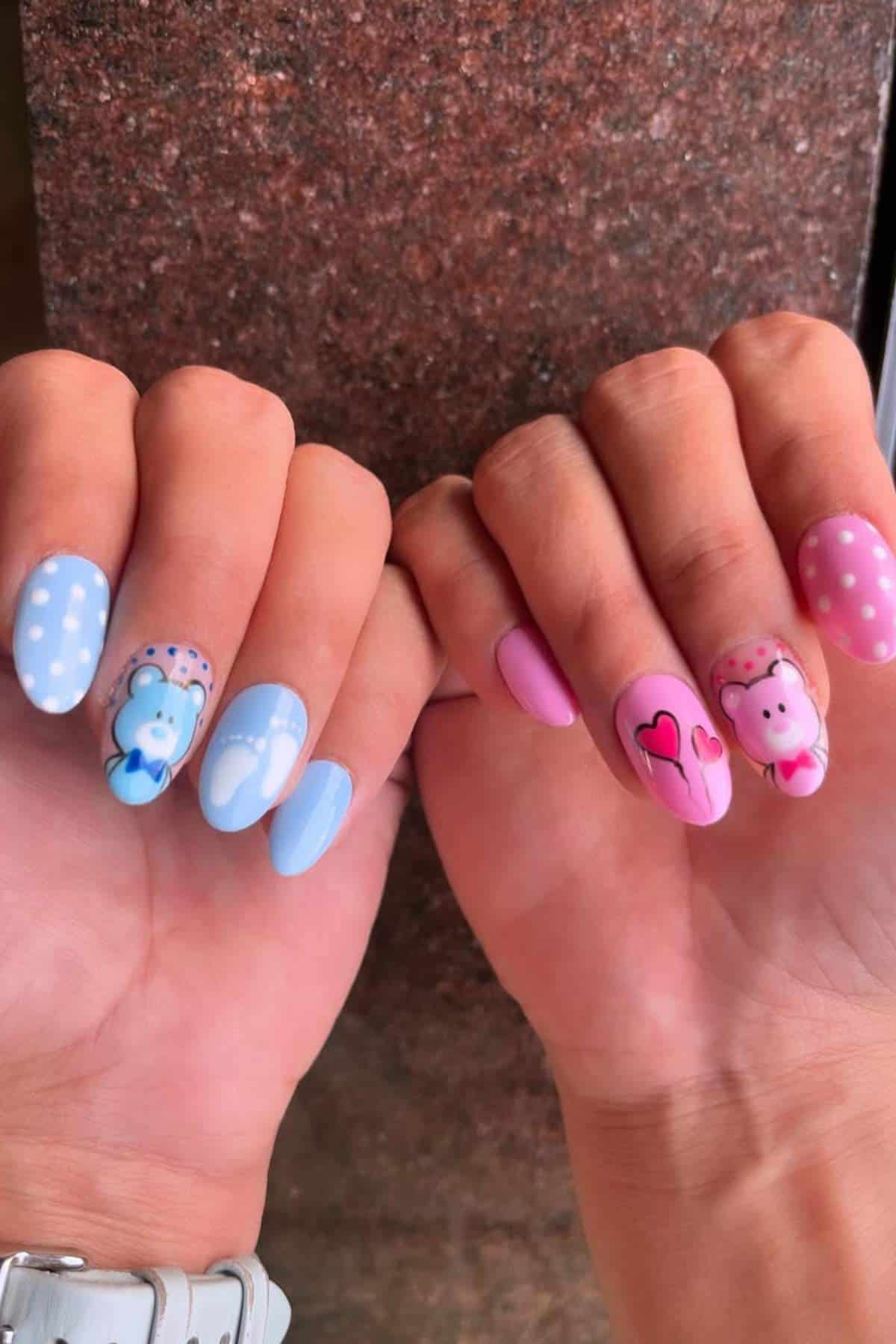 Two hands with manicured nails; left hand has blue polish with polka dots, a bear, and hearts, while right hand has pink polish with polka dots, hearts, and a monkey design.
