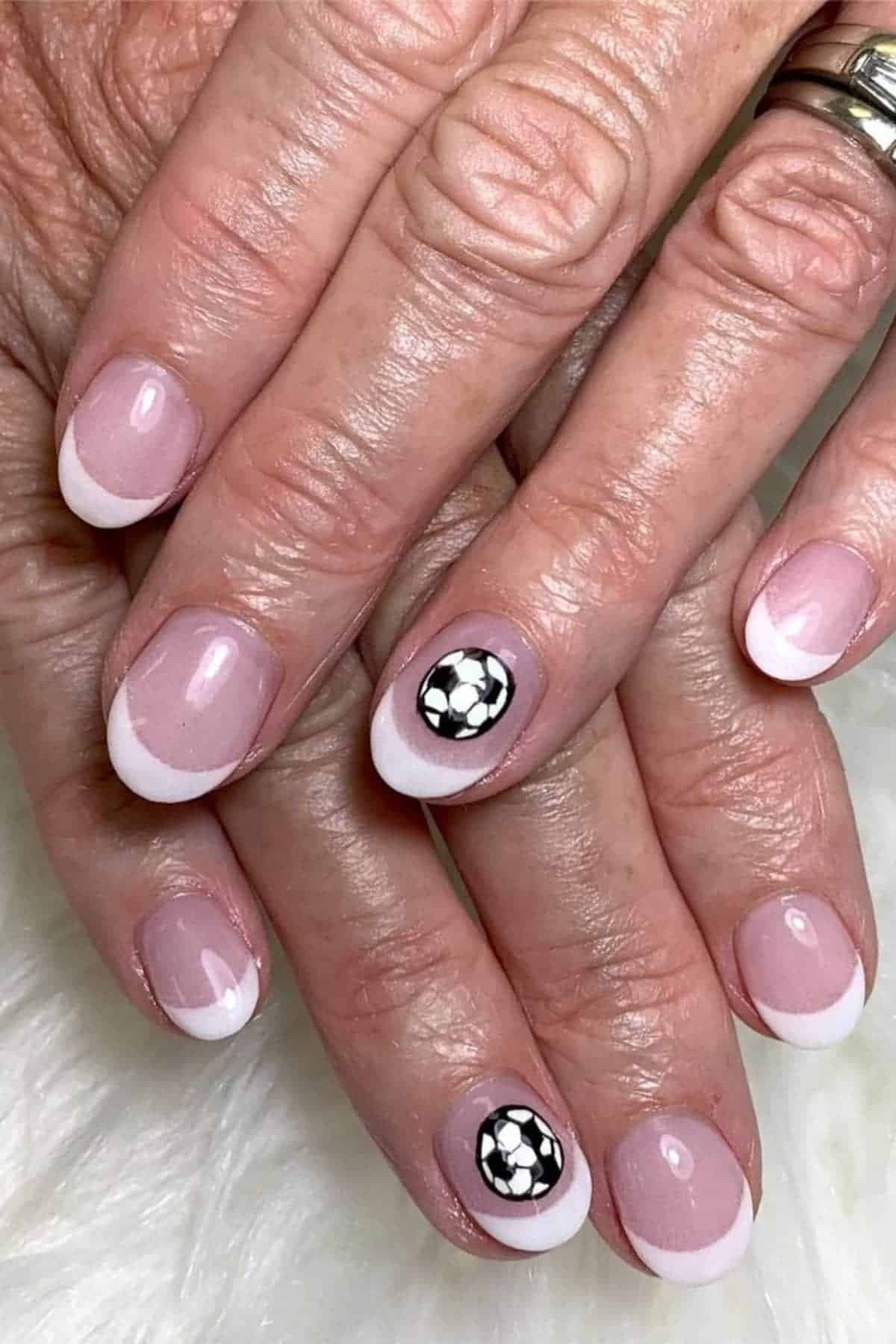 Hands with a French manicure; one nail on each hand features a black and white soccer ball design.