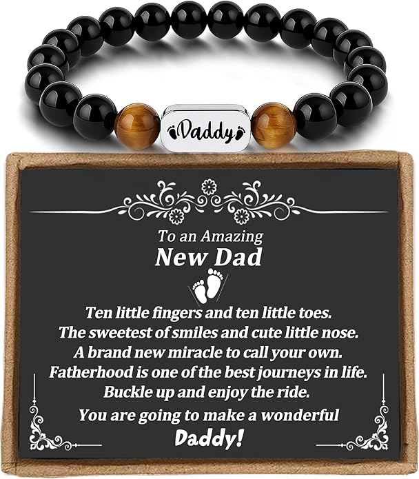 A black beaded bracelet with "Daddy" on a metal plate is displayed above a plaque with a message celebrating a new dad and fatherhood.