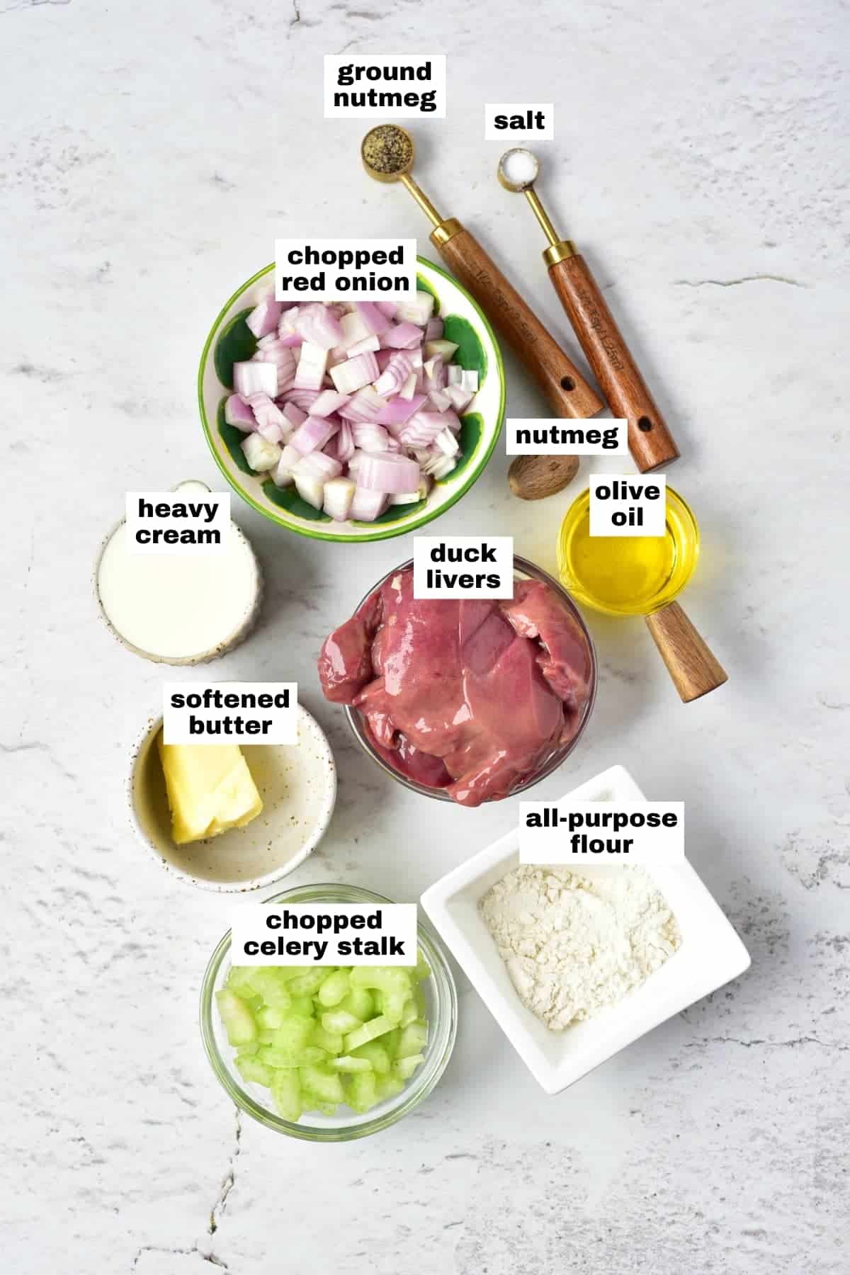 Ingredients for a recipe displayed on a white surface: chopped red onion, celery, duck livers, flour, softened butter, heavy cream, olive oil, salt, and ground nutmeg.