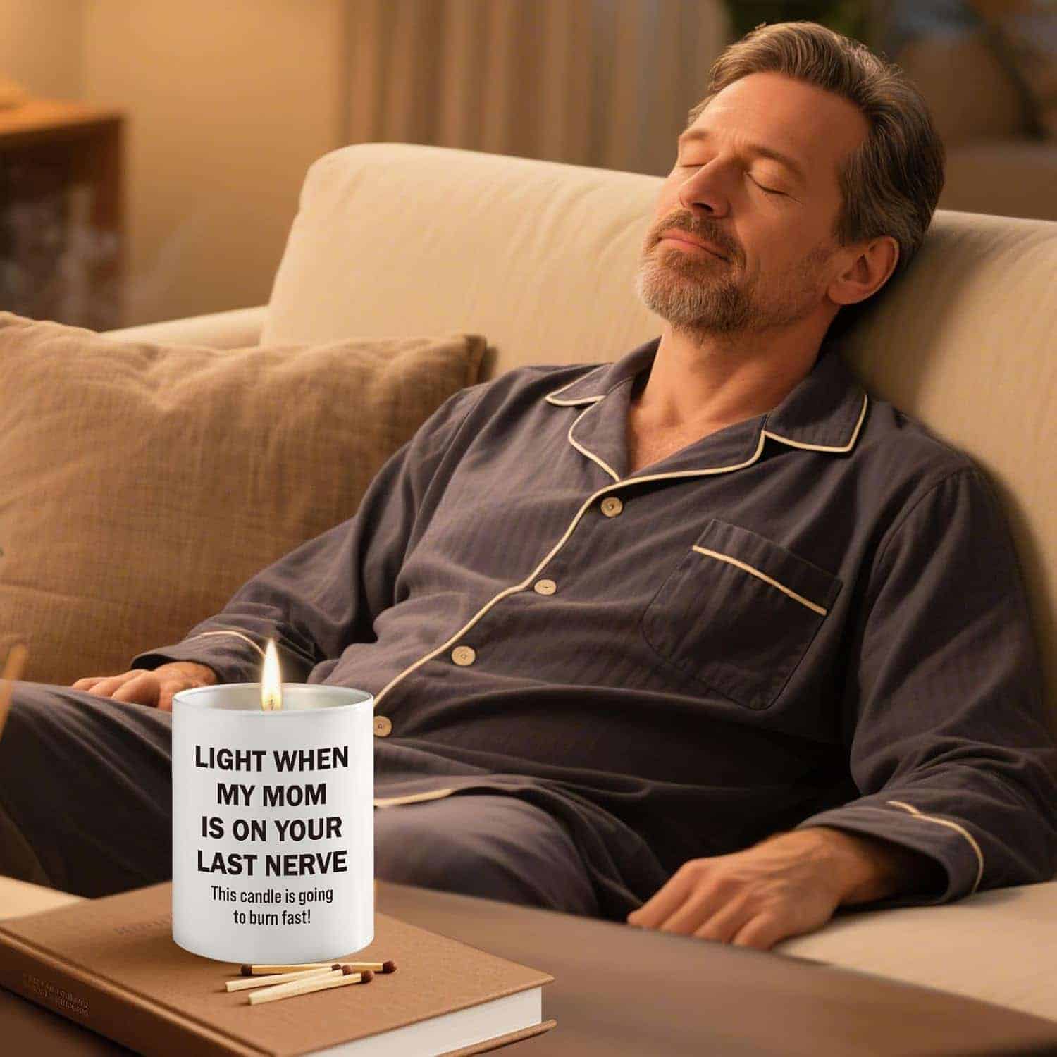 A man in pajamas relaxes with his eyes closed on a sofa. In front of him is a lit candle labeled, "Light when my mom is on your last nerve. This candle is going to burn fast!.