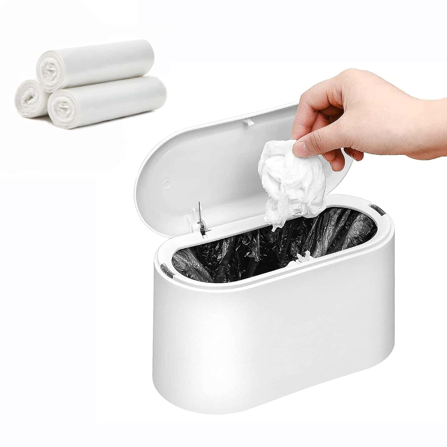 A hand placing a tissue into a small white trash bin with a black liner; three rolled trash bags are shown in the background.