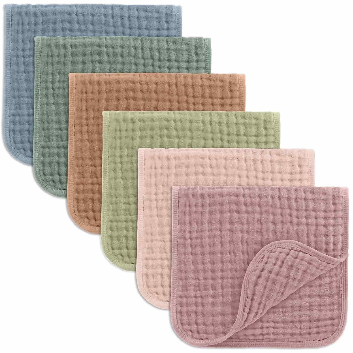 Five textured washcloths in blue, brown, green, beige, and pink are arranged in a staggered stack, with the corner of the front cloth folded to show the back.