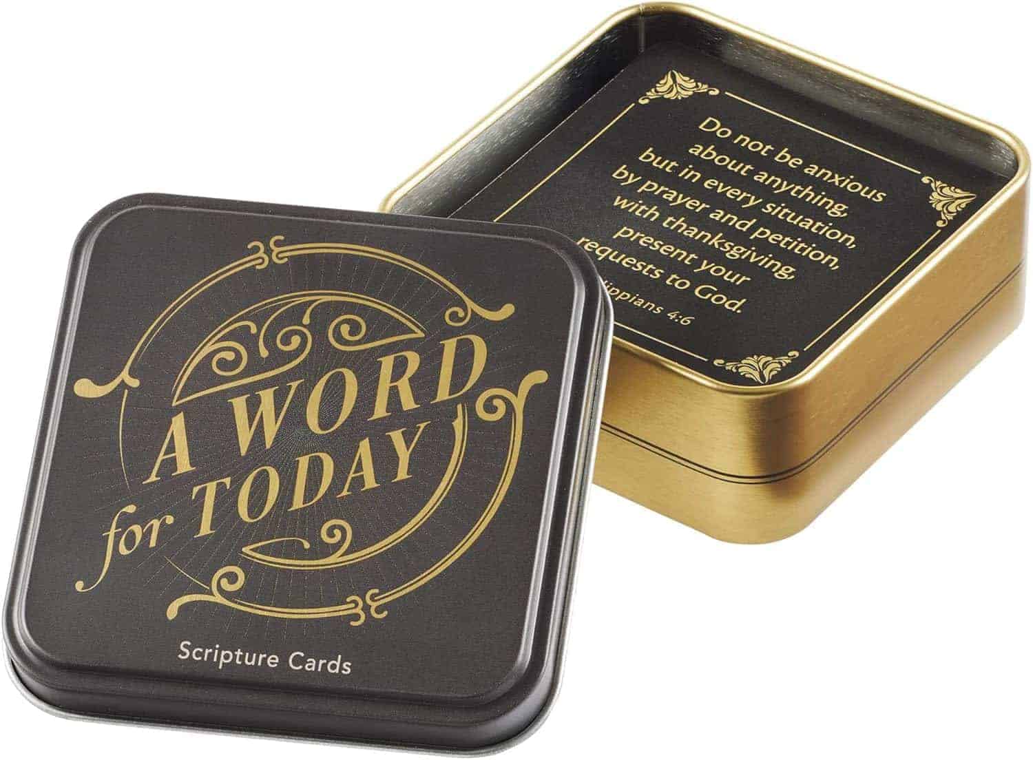 A square tin labeled "A Word for Today Scripture Cards" with the lid off, revealing a card inside displaying a Bible verse from Philippians 4:6.