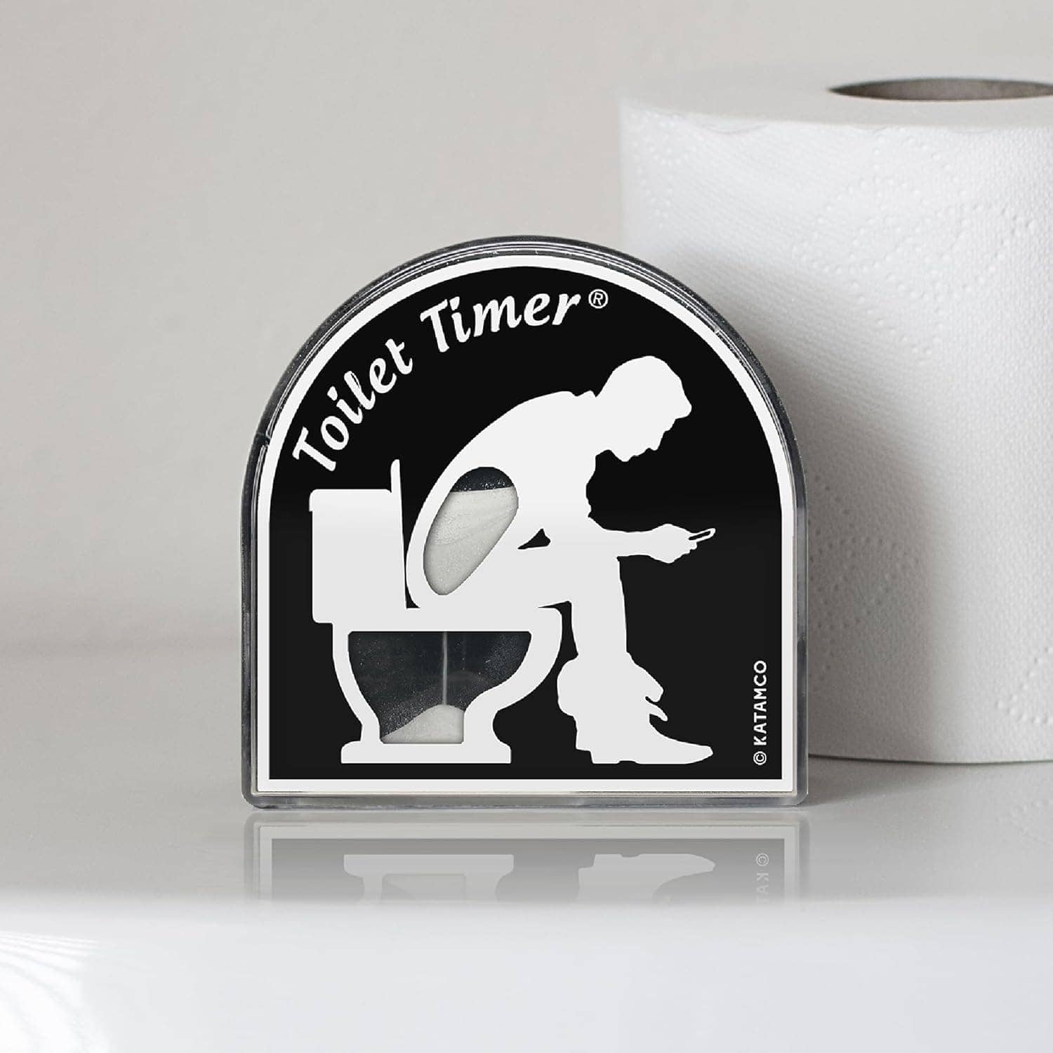 A sand timer labeled "Toilet Timer" shows a silhouette of a person sitting on a toilet and looking at a phone, with a roll of toilet paper in the background.