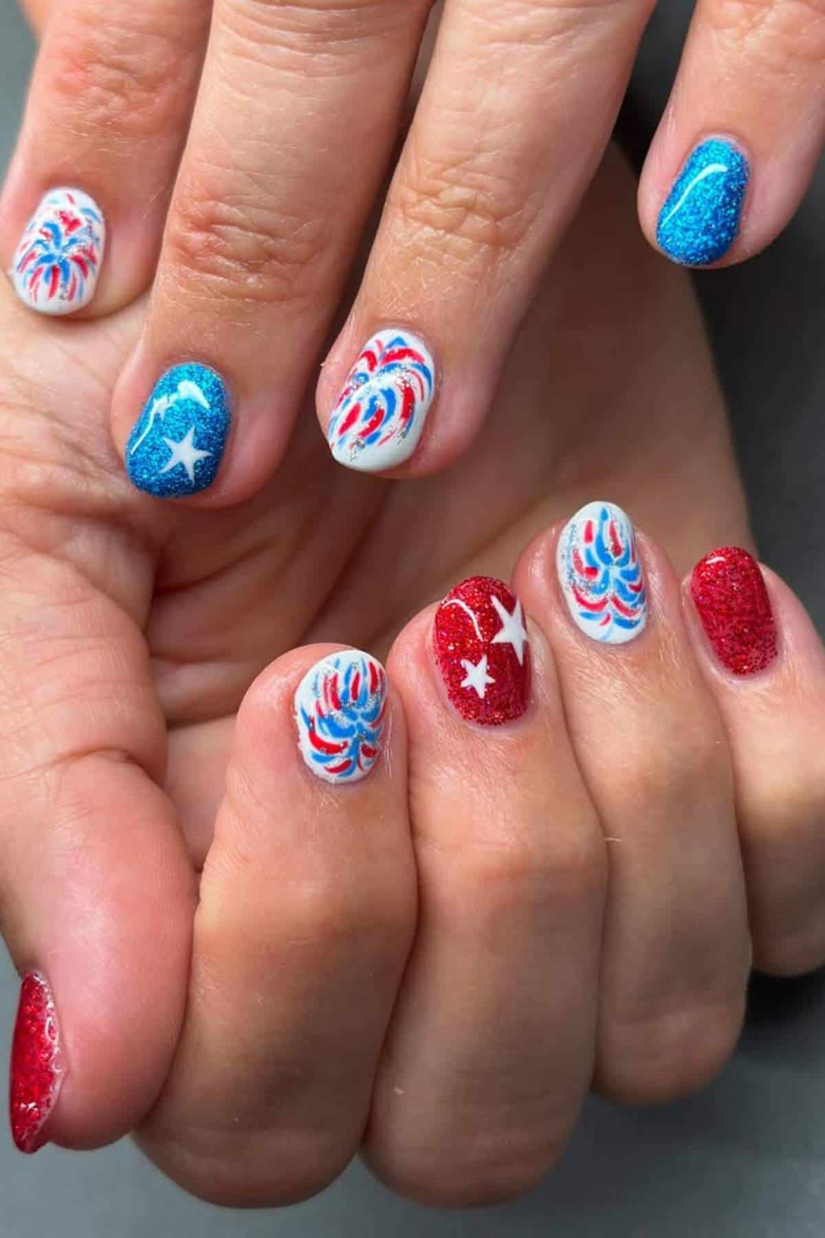 Red, white, and blue nails with firework and star designs.
