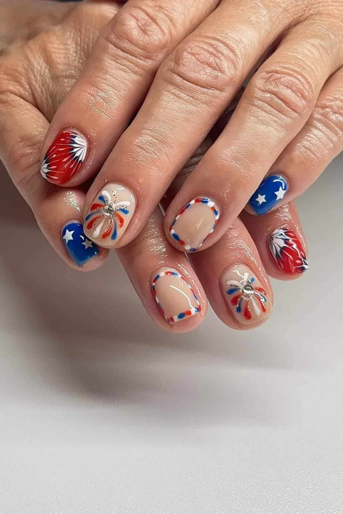 Red, white, and blue themed nails with stars, fireworks, and French tips.