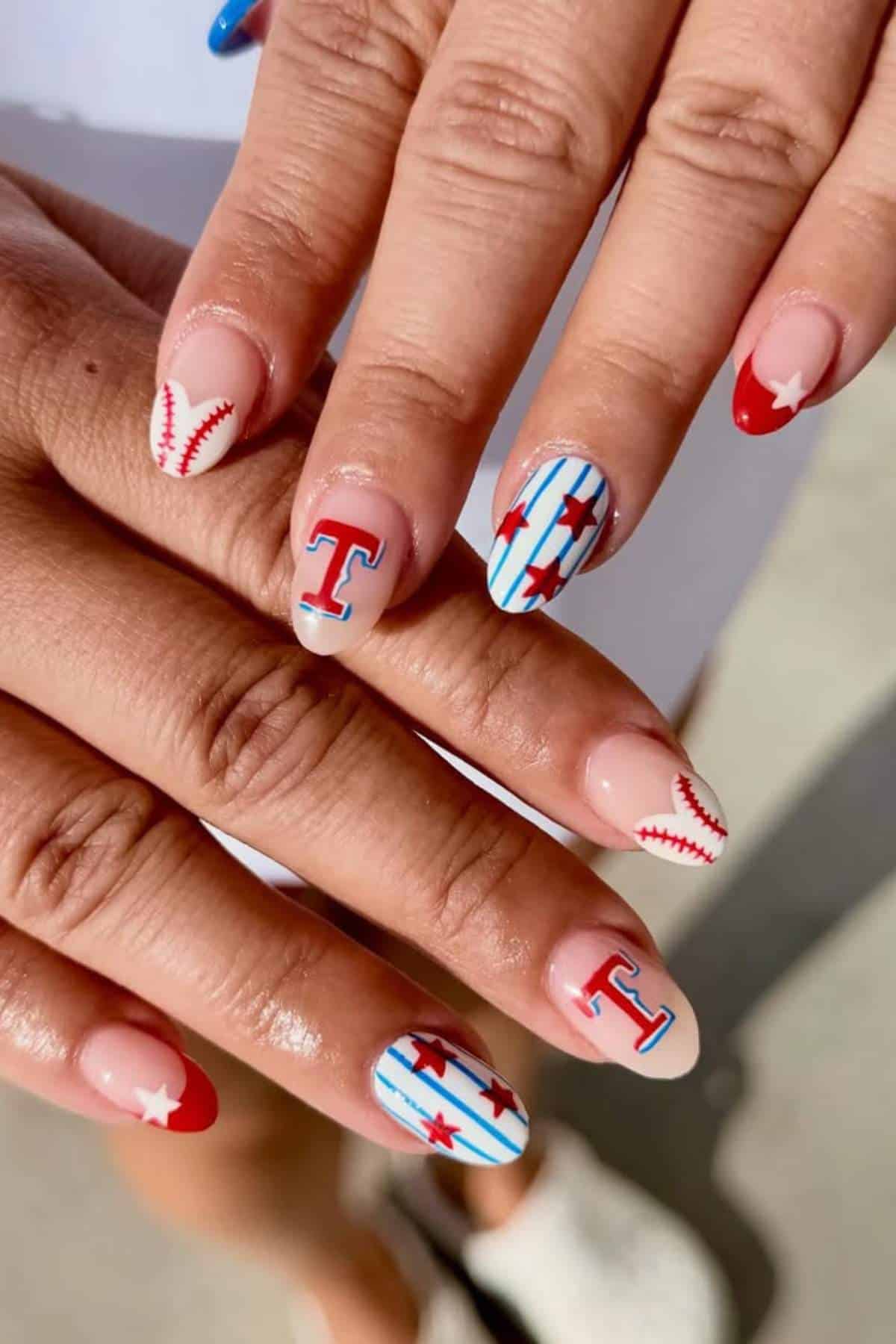 Hands with manicured nails featuring Texas Rangers baseball team designs, including baseball stitching, stars, the letter "T," and red, white, and blue colors.