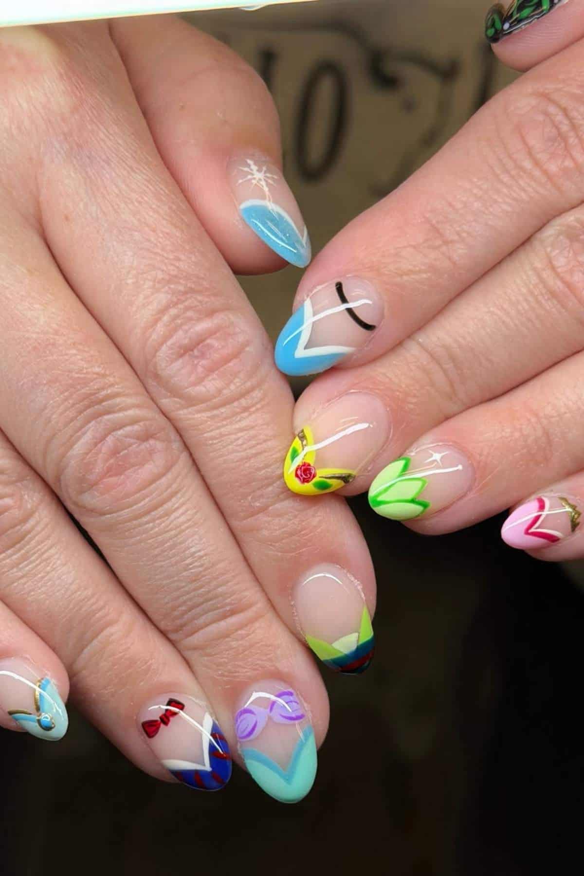 Hands with almond-shaped nails featuring colorful nail art inspired by Disney princesses, each nail displaying a distinct design and color scheme.
